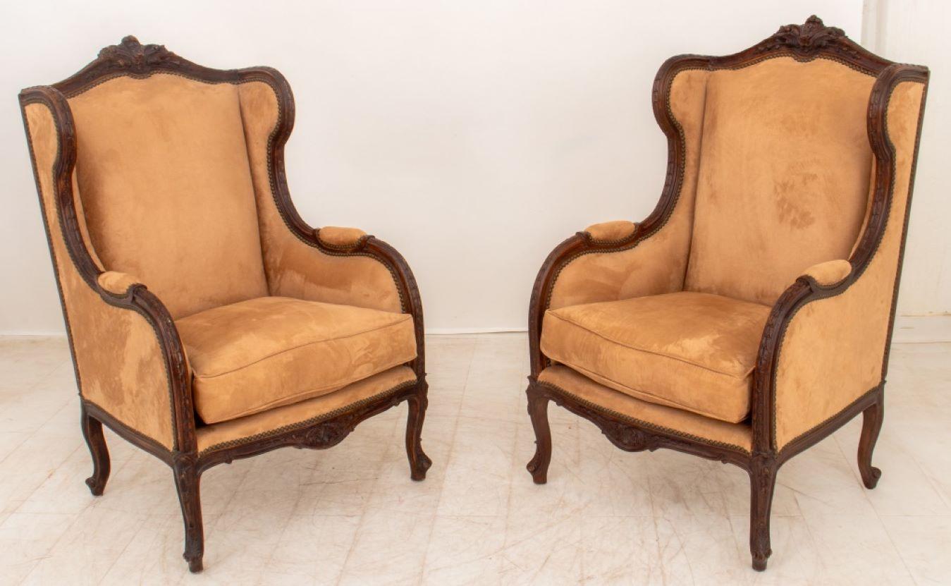 Paire de bergères de style Louis XV recouvertes de velours, cadre en noyer et garniture rivetée, chacune recouverte de velours beige au-dessus de pieds avant cabriole cannelés et de deux pieds arrière effilés. 47,5