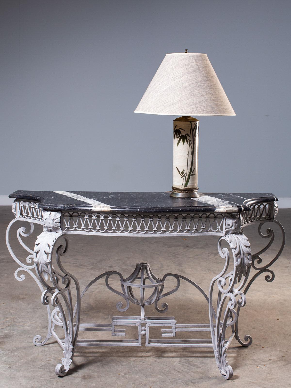 A beautiful Louis XV style vintage French painted iron console table circa 1940 with the original grey marble top shaped to fit the exuberant profile of the iron base. This French console table harks back to the extraordinary creations developed by