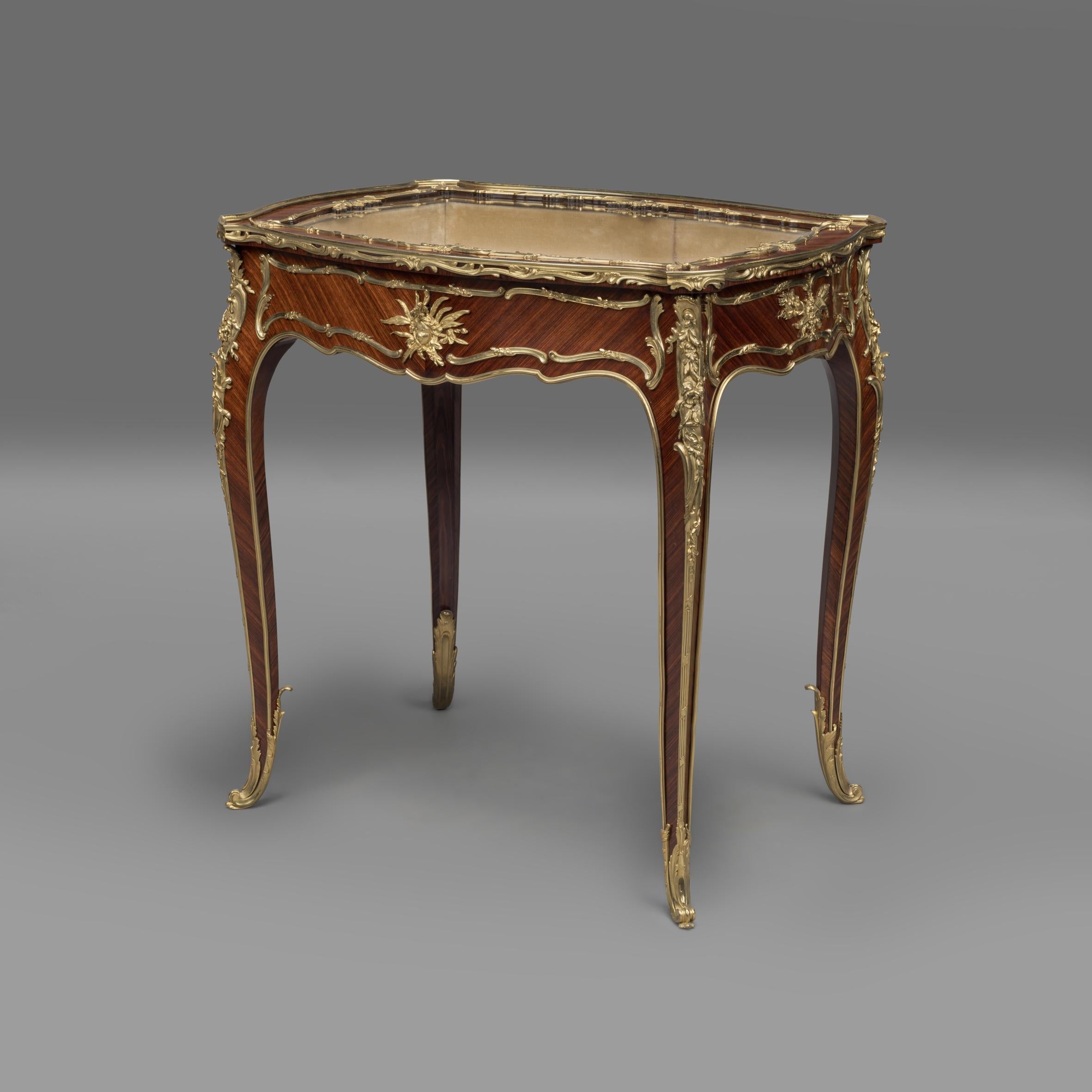 Vitrine de table en bronze doré de style Louis XV, par François Linke, les montures étant dessinées par Léon Messagé.

Numéro d'index 131.

Cette élégante vitrine de table présente un plateau vitré à charnière s'ouvrant sur un intérieur tapissé