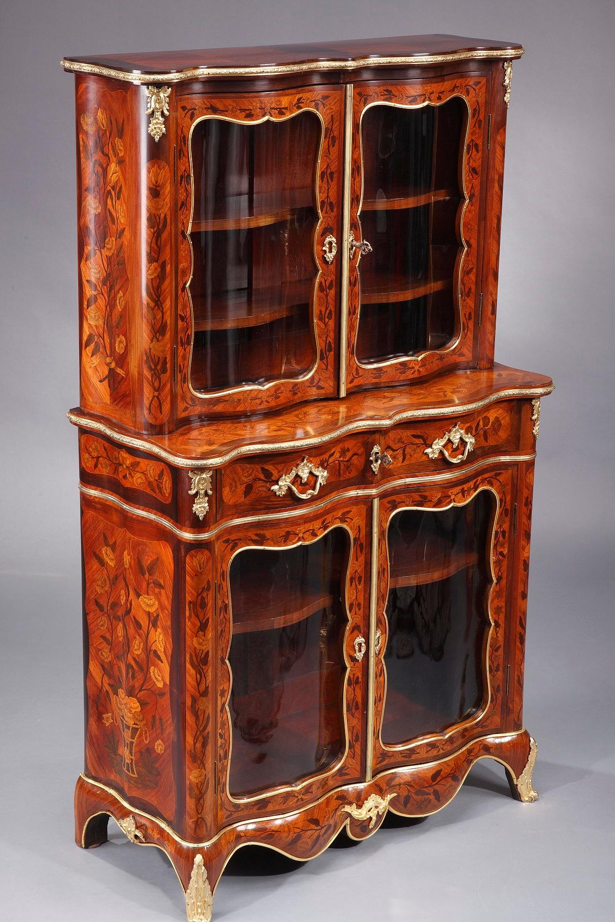 Louis XV-style vitrine crafted of veneered rosewood, amaranth and satinwood. Elegantly set upon cabriole legs, the showcase is distinguished by a luxurious marquetry decoration featuring floral pattern and vases. The satinwood is an exotic wood with