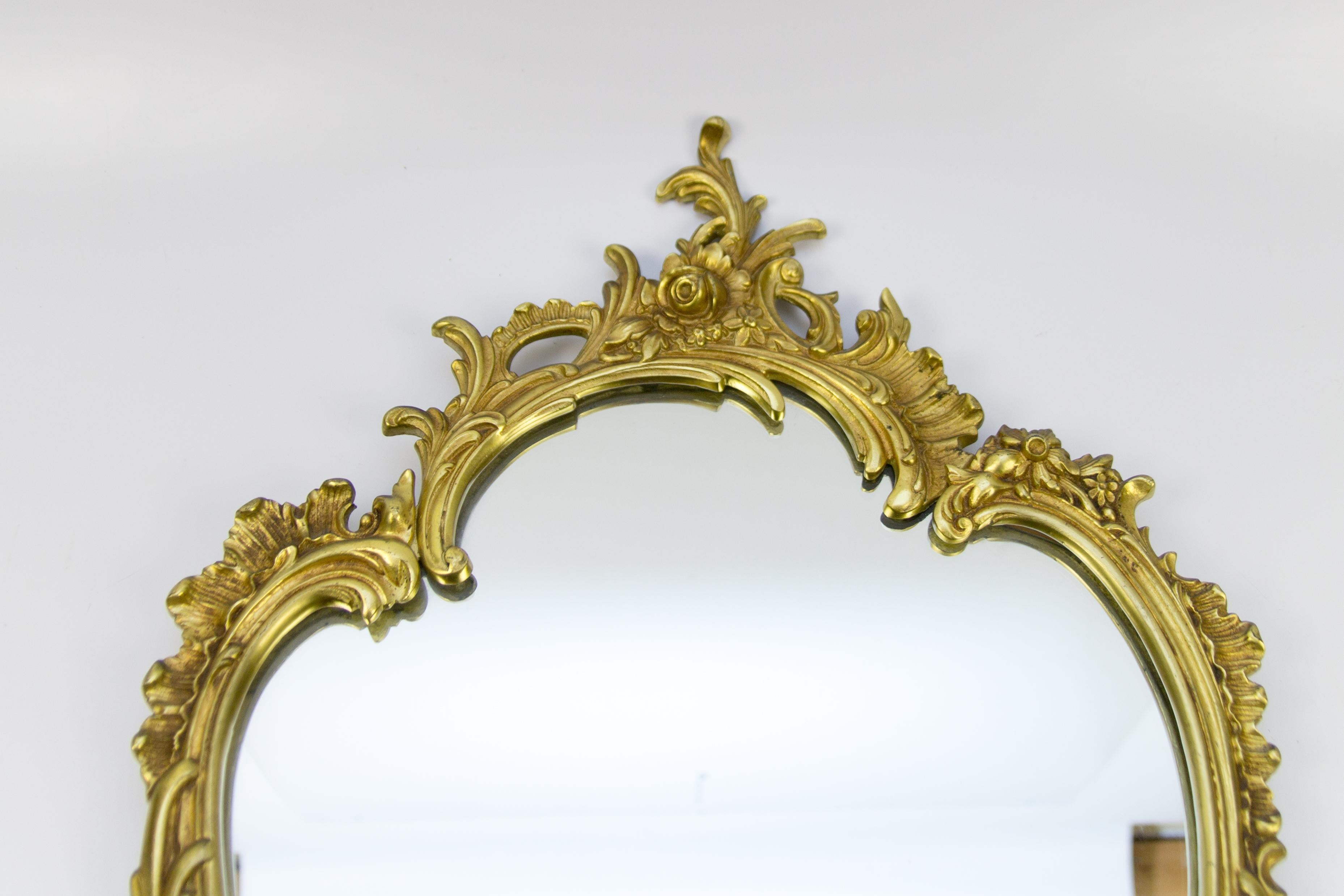 Beautiful oval shaped French Rococo style or Louis XV style wall mirror in bronze, decorated with C-scrolls, rocaille and floral motifs, circa 1950s.
Dimensions: Height 70 cm / 27.55 in, width 42 cm / 16.53 in depth, 2 cm / 0.78 in.