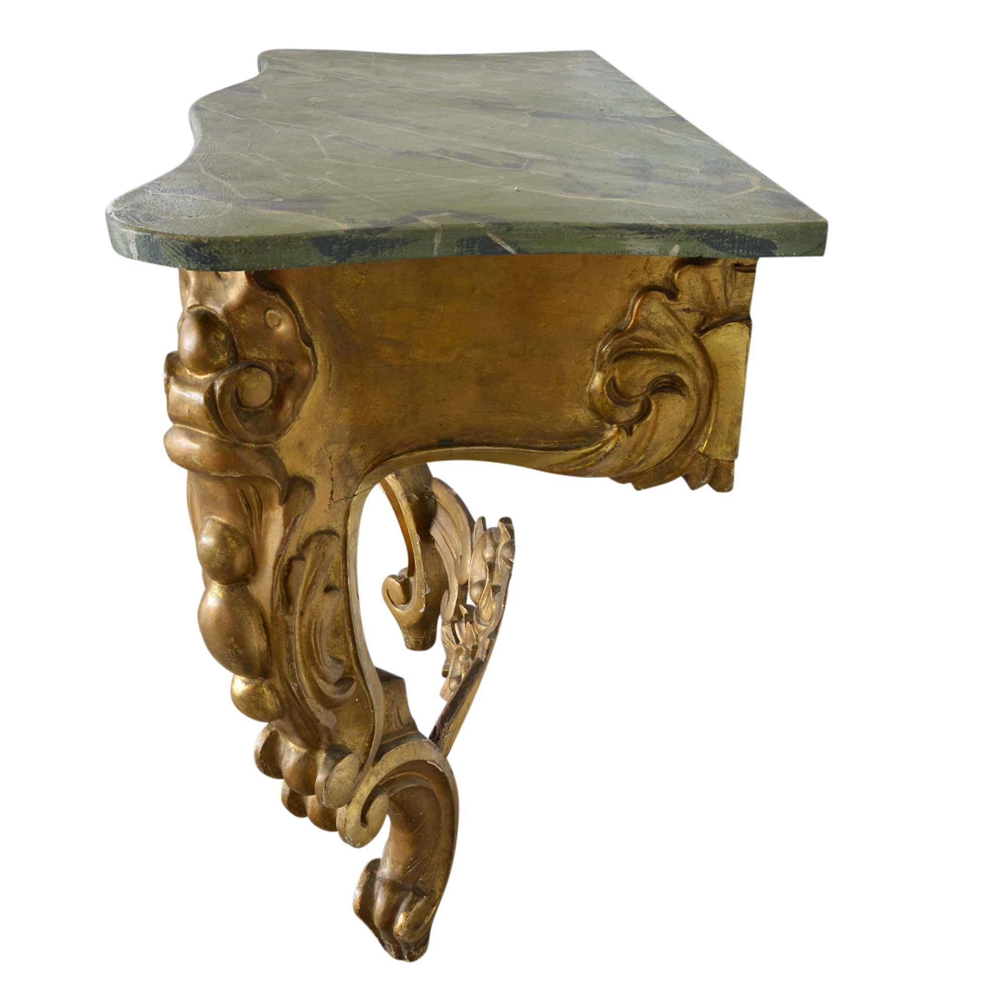 An outstanding carved giltwood console in the Louis XV style, it was likely carved early in the 20th century. The faux marble top is expertly painted to appear as rich green marble. The console top sits atop a refined base of giltwood with scrolled