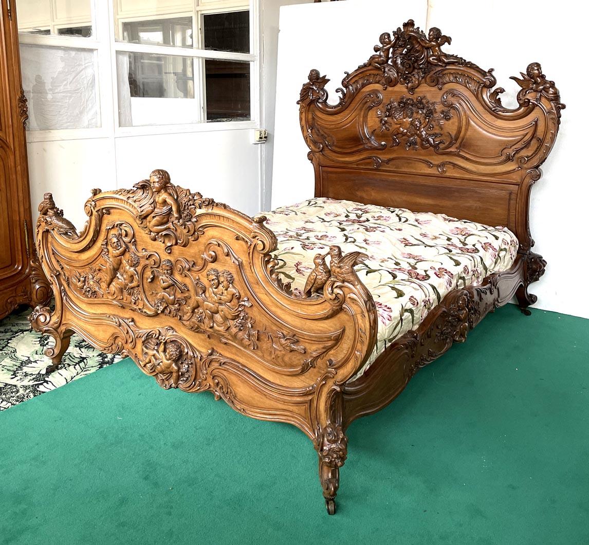 Carved walnut bedroom set in Louis XV style, composed of:

Bed:
Headboard height: 171 cm
Footboard height: 99 cm
Width: approx. 171 cm (including footboard carvings)
Depth: approx. 218 cm (including carvings)
Mattress: 137 cm x 187.5 cm – Height: 26