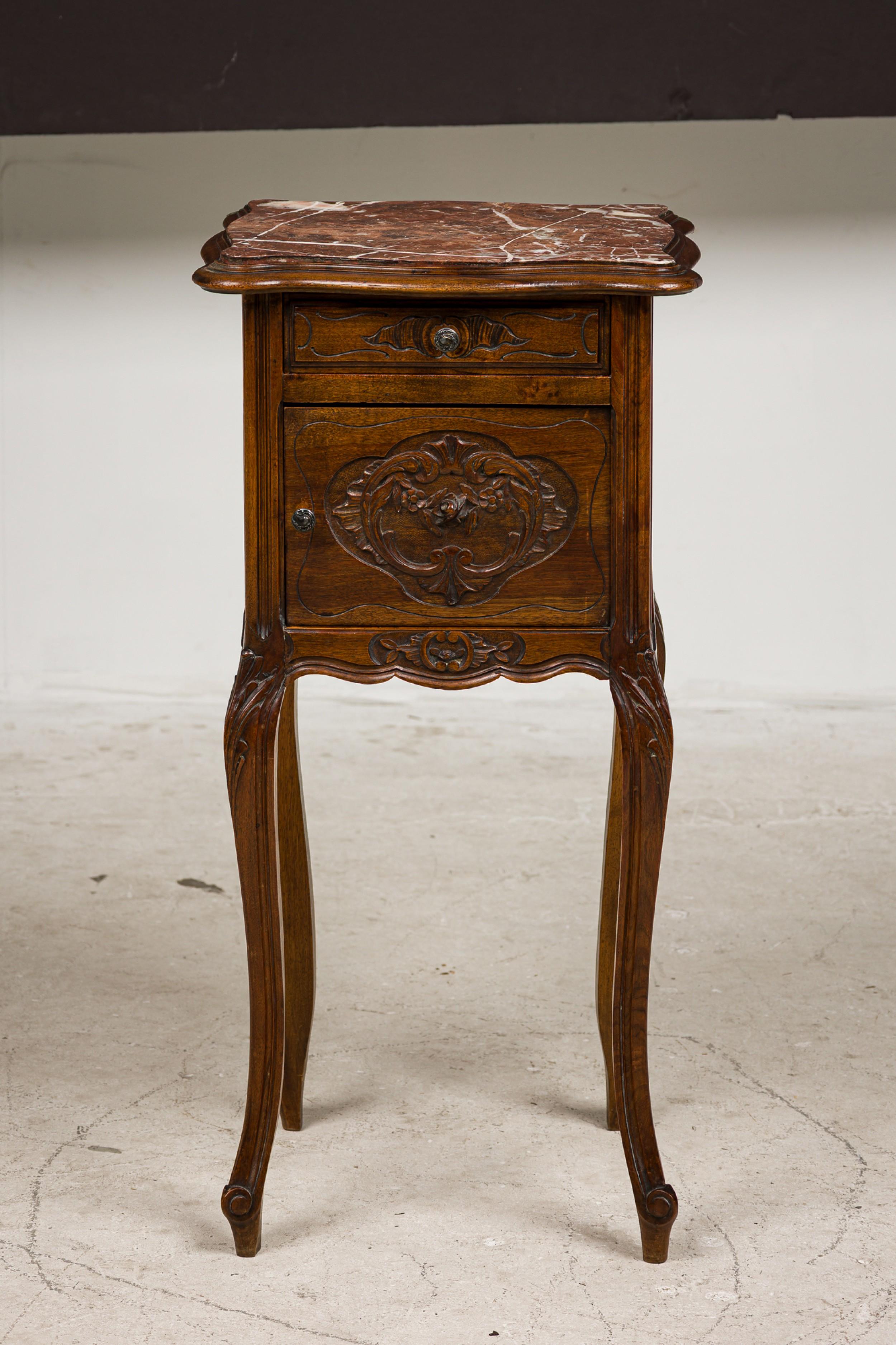 Louis XV style walnut bedside commode with a rouge shaped marble top over single drawer over a cabinet with a carved floral door front having a white porcelain insert,