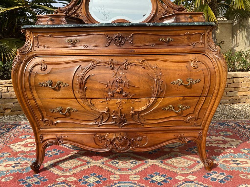 Superb and imposing walnut chest of drawers carved with foliage and bouquets of roses in the Louis XV style. It is surmounted by a sea green marble. It opens with two large drawers, is adorned with a magnificent mirror, richly carved and enhanced