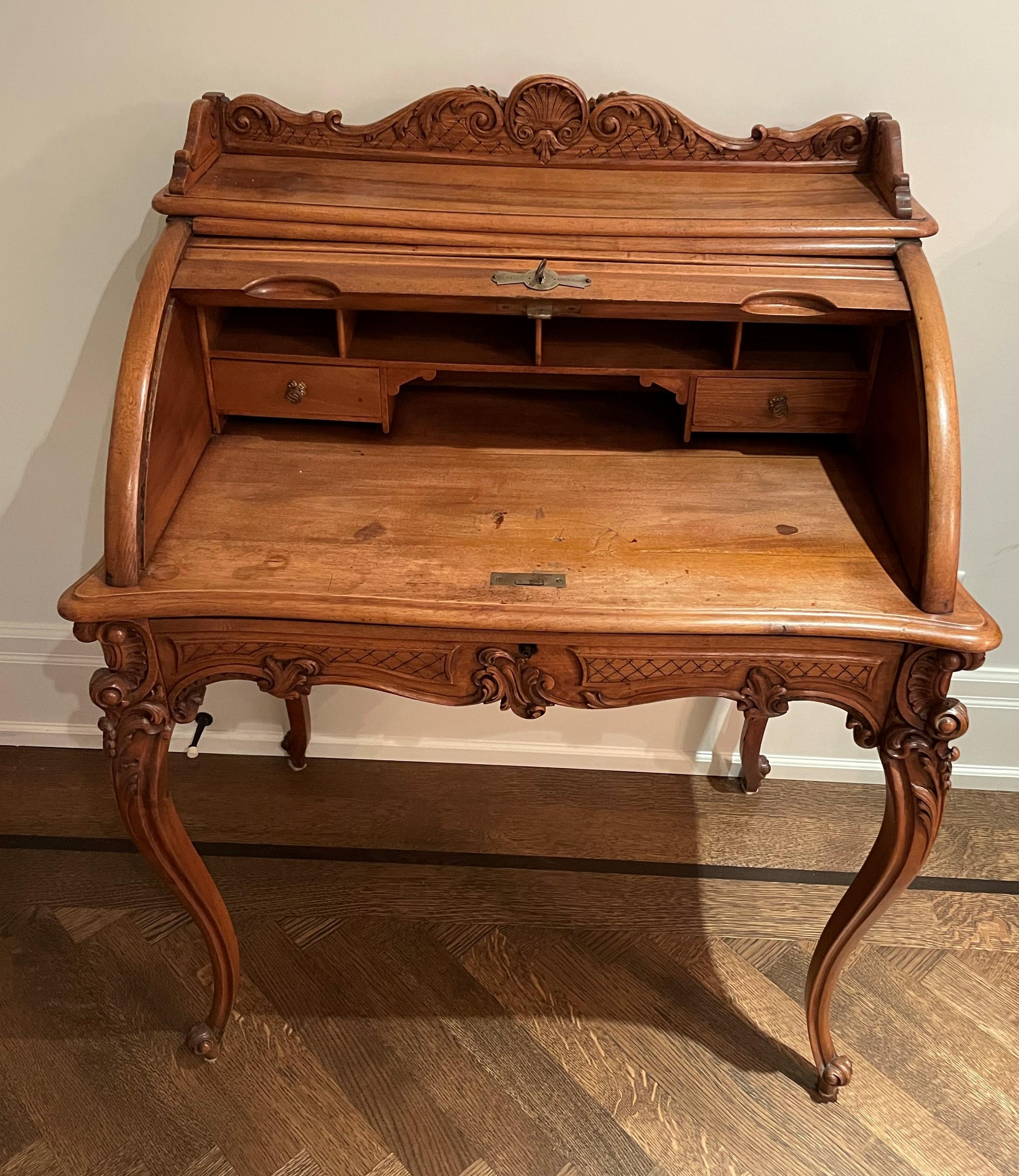 A charming roll top desk in the style of Louis XV made in walnut having interesting and attractive hand carved elements. The size is perfect to fit in smaller place in your home. it is highly decorative and functional. There is a large drawer as