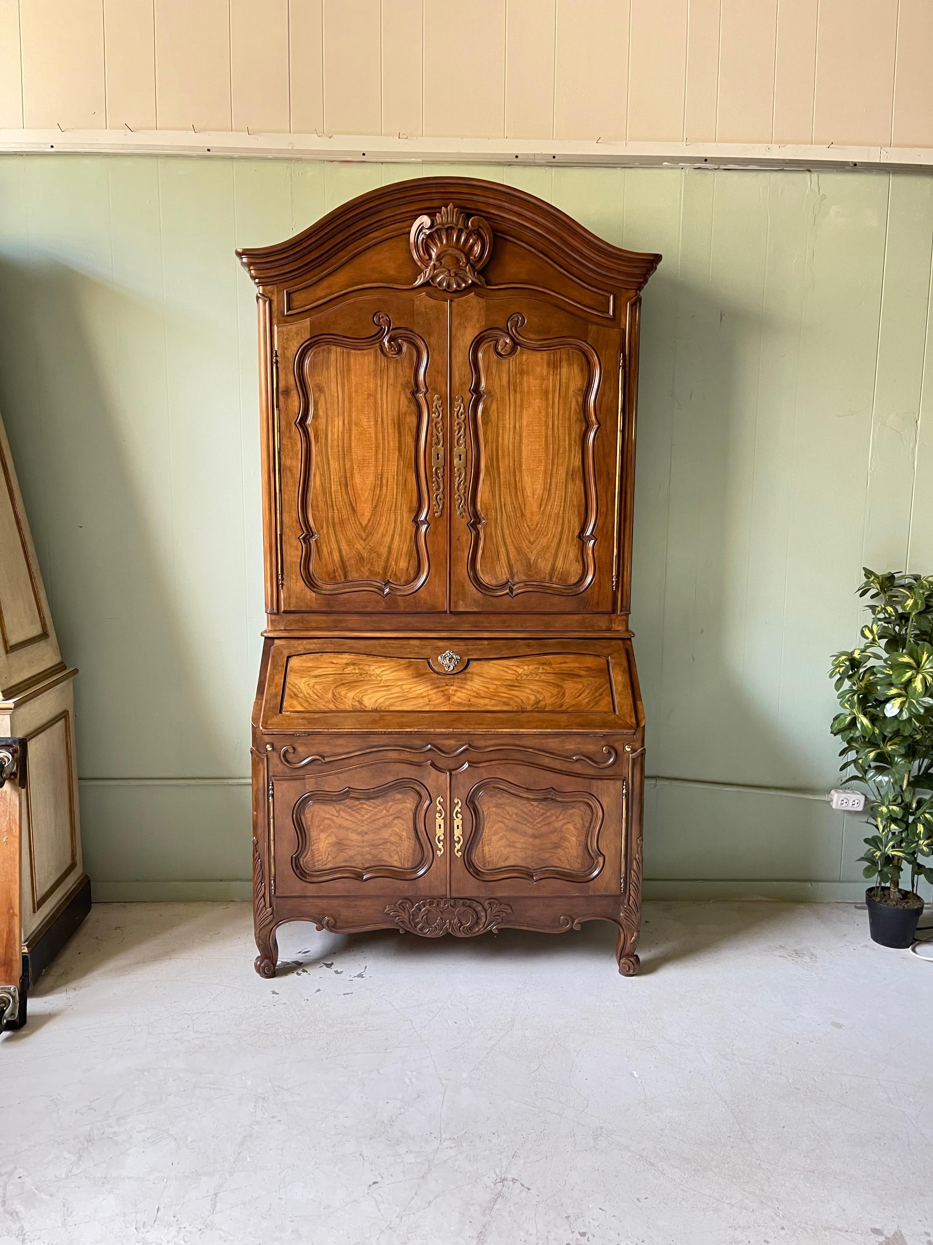 20th Century Collector's Edition secretary cabinet by Baker Furniture Company in the French style of Louis XV. The secretary is made of upper and lower cabinets made of carved walnut with working locks and keys. The upper cabinet features an arching