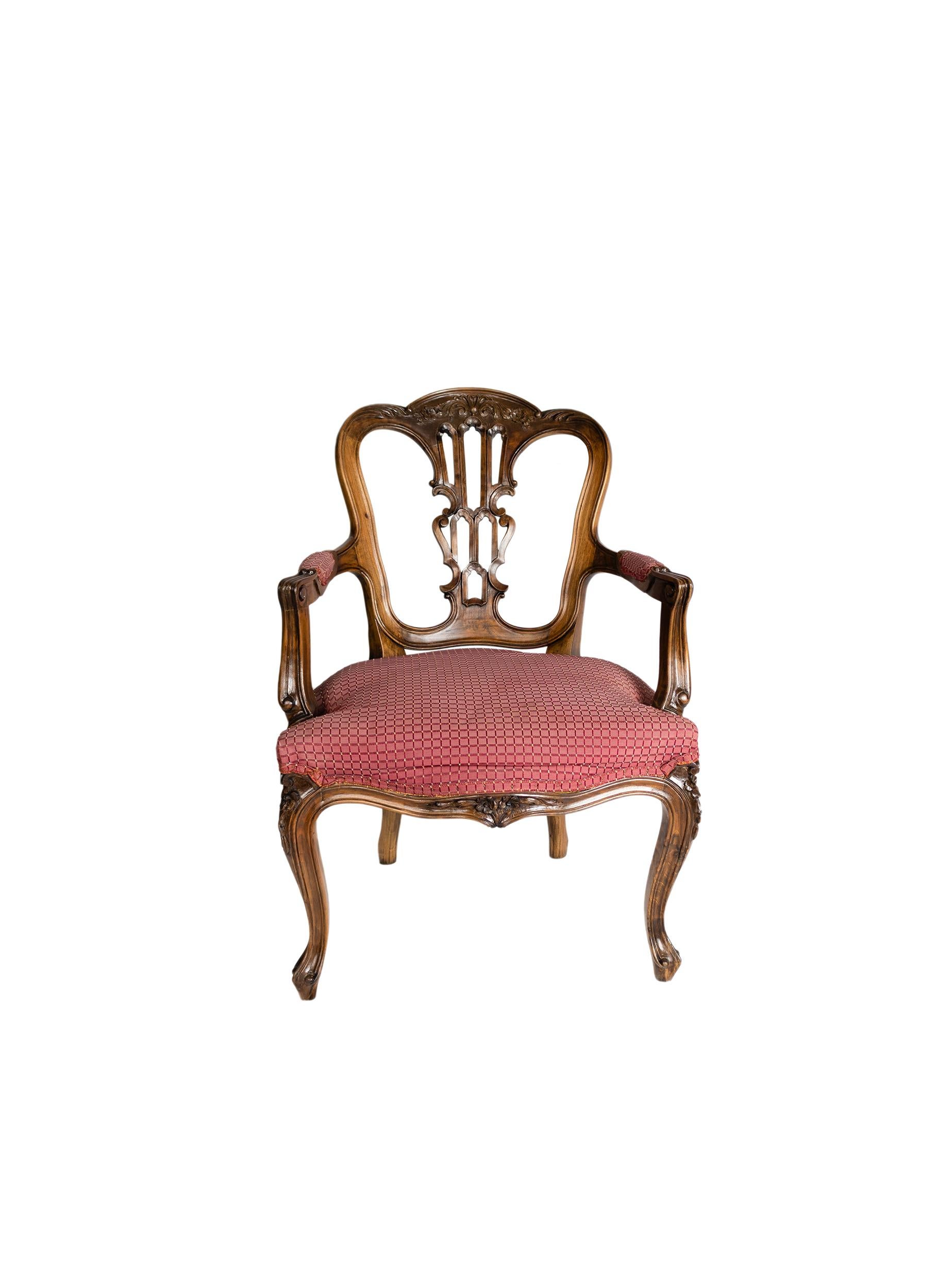 Sillón (fauteuil) de estilo veneciano, de madera de nogal, con tallas vegetaristas, respaldo curvado de tabla central, brazos abiertos y patas curvadas, y asiento tapizado en tela roja estampada.