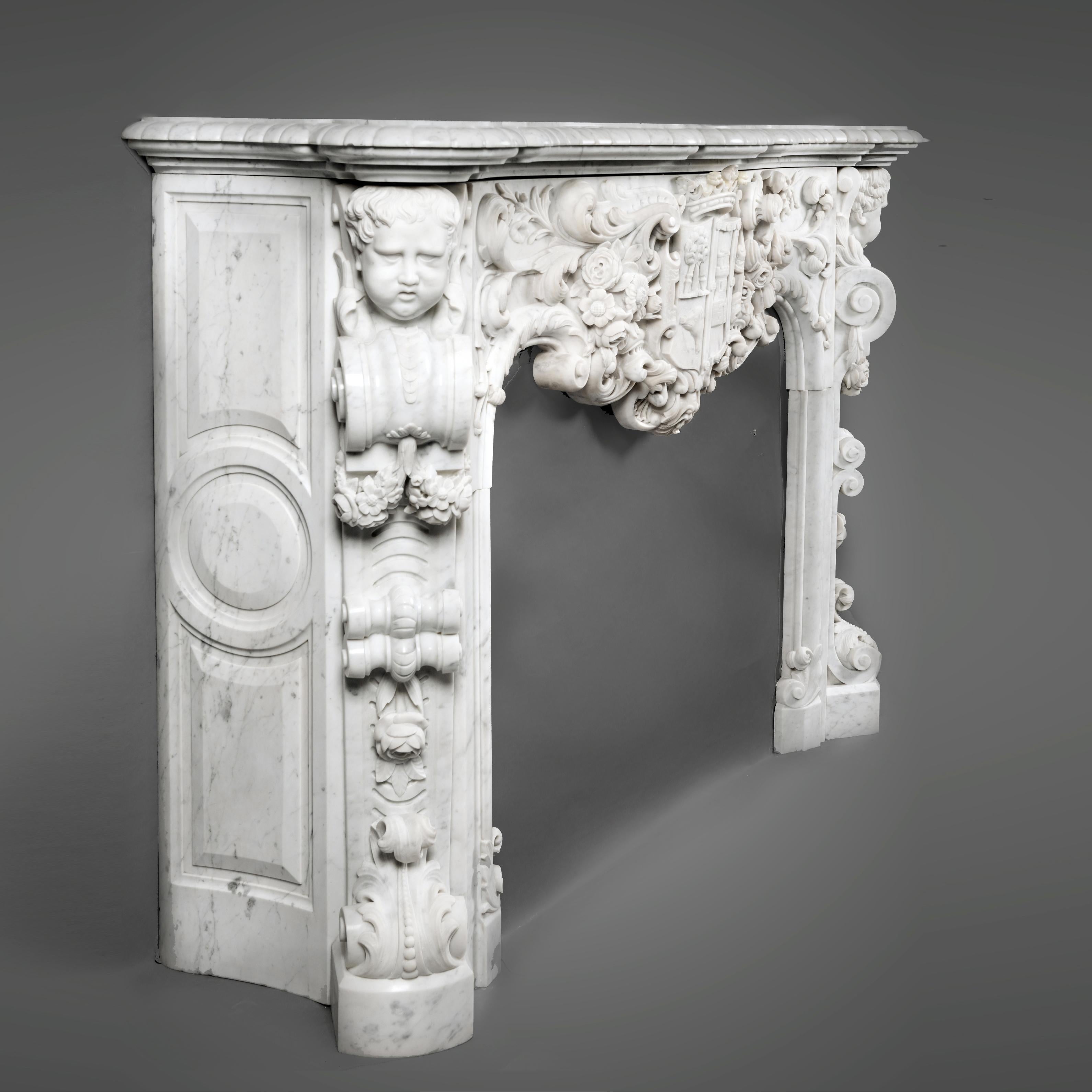 A magnificent and highly important Louis XV style white Carrara marble figural fireplace.

This exceptional marble fireplace has a shaped mantel above a frieze finely carved with scrolling acanthus, flowers and a grotesque mask, centred by a
