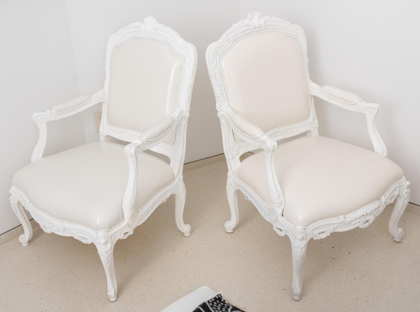 Louis XV style white lacquered arm chairs or fauteuils a la reine, the scrolling acanthus-carved crestrails centering scallop shells, with straight arms above a shaped square seat rail garland-festooned seat rails, on four cabriole legs terminating