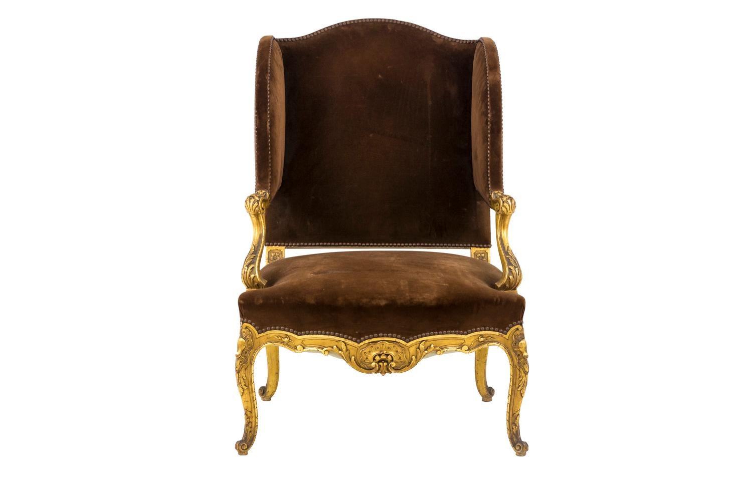Louis XV style wing chair in giltwood standing on four cabriole legs ending by volute shaped acanthus leaves adorned with a foliage rocaille cartouche.
Scalloped apron centred by a c-crest and decorated with acanthus leaves and scrolls.
Arm