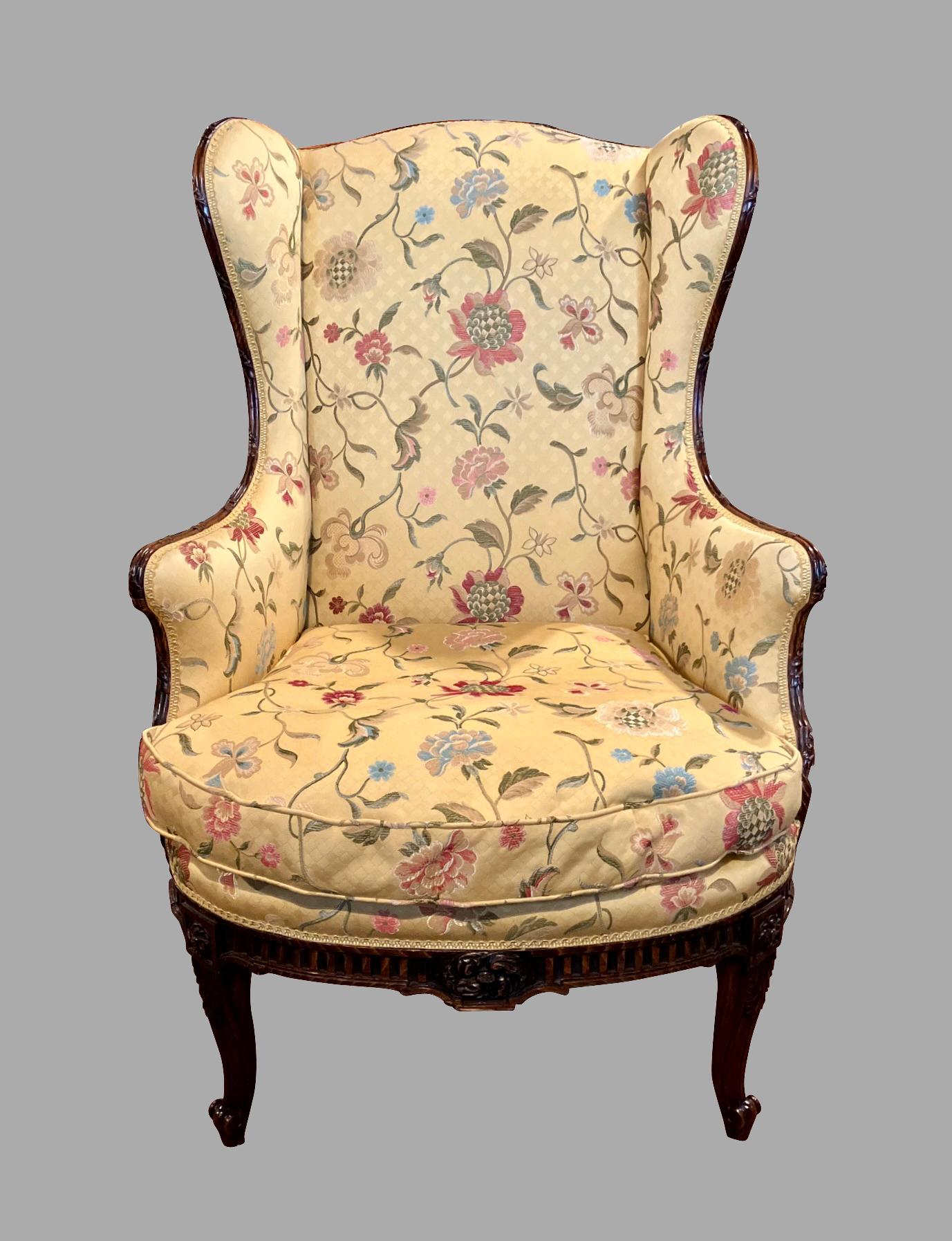A fine quality Louis XV style lounge chair beautifully upholstered in yellow silk fabric with an overall foliate design. The well-carved hardwood frame starts at the top of the piece and ends in upturned front legs headed with square floral paterae