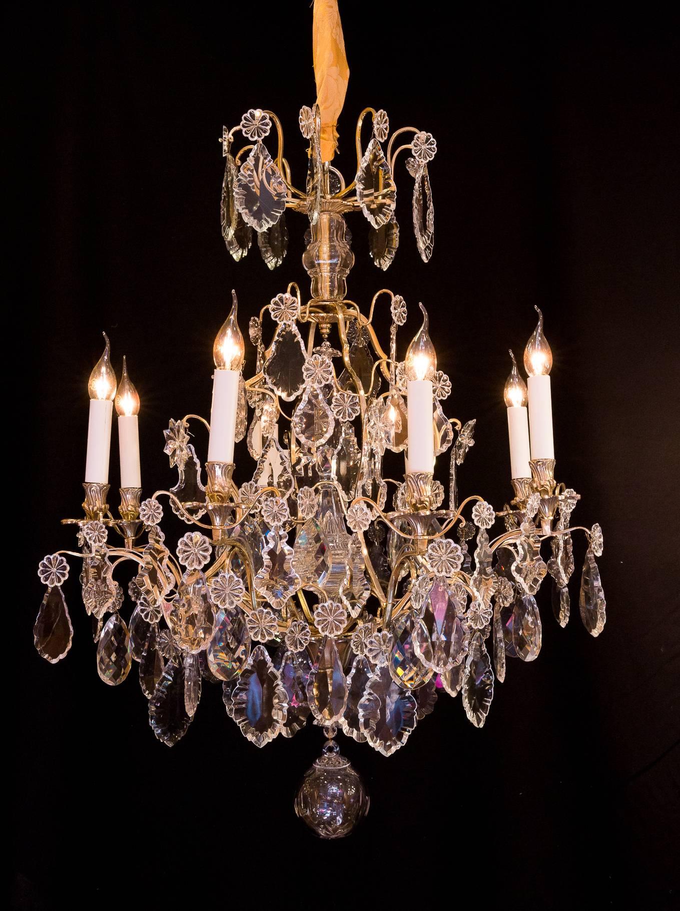We are pleased to present you, an elegant gilt bronze and cut-crystal, chandelier in the classic French Louis XV style. 
Our chandelier is composed of eight perimeter arm lights. Beautiful quality white cut-crystal pieces, plaques, one large dagger