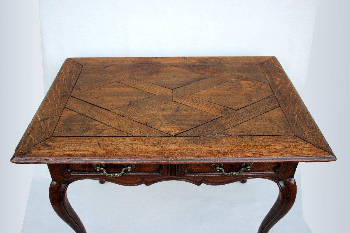 Louis XV period table in oak, from the Ile-de-France region.
Parqueted top resting on a curved and molded base finished with scrolls, four moving crosspieces, two molded drawers on the front with original bronze handles.
A missing lock.
This table