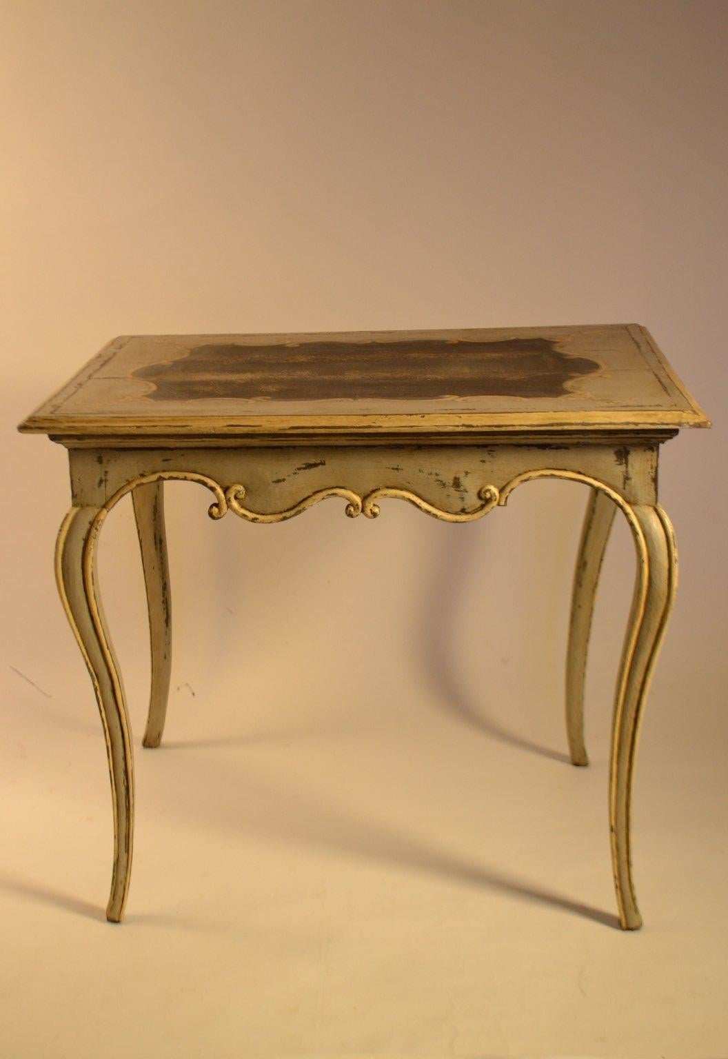 Louis XV period table with a dainty and finely carved apron in a bow transom pattern and elegant cabriole legs. The top is painted with a dark interior and C-scroll border with bell flower style tassels.