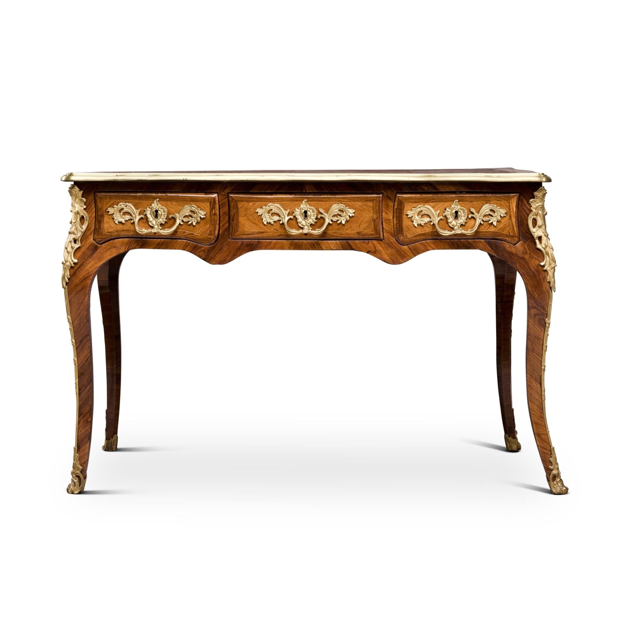 Questo elegante bureau plat Luigi XV, risalente al 1750 circa, mostra la squisita maestria dell'epoca. Realizzata in legno di tulipano e kingwood, la scrivania presenta un lussuoso piano in pelle che offre una sofisticata superficie di