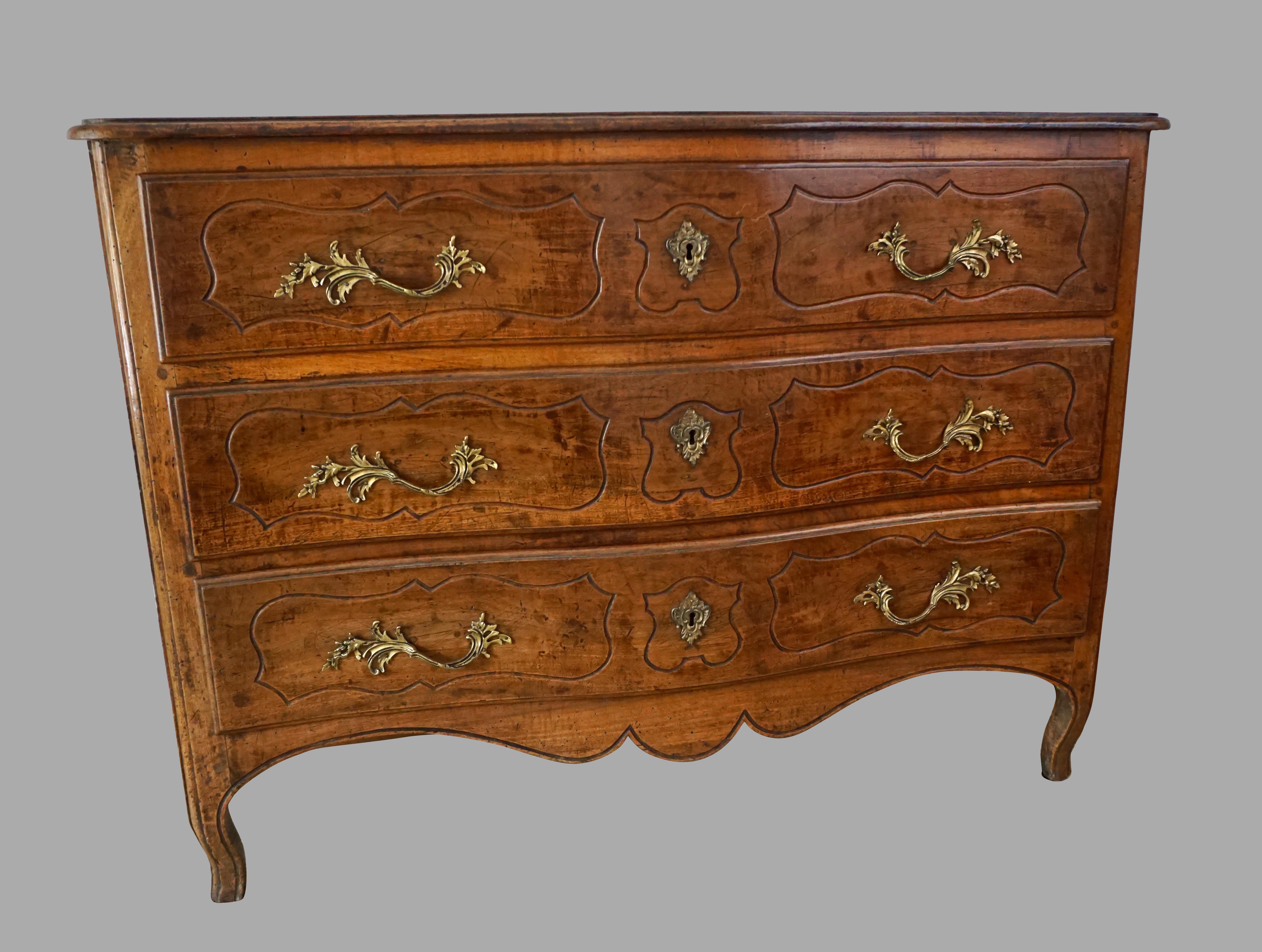 A French Louis XV period provincial 3 drawer walnut serpentine commode, the top with a molded edge above 3 drawers, each with incised paneled decoration, the paneled sides similarly decorated, the base with a shaped apron, all resting on short