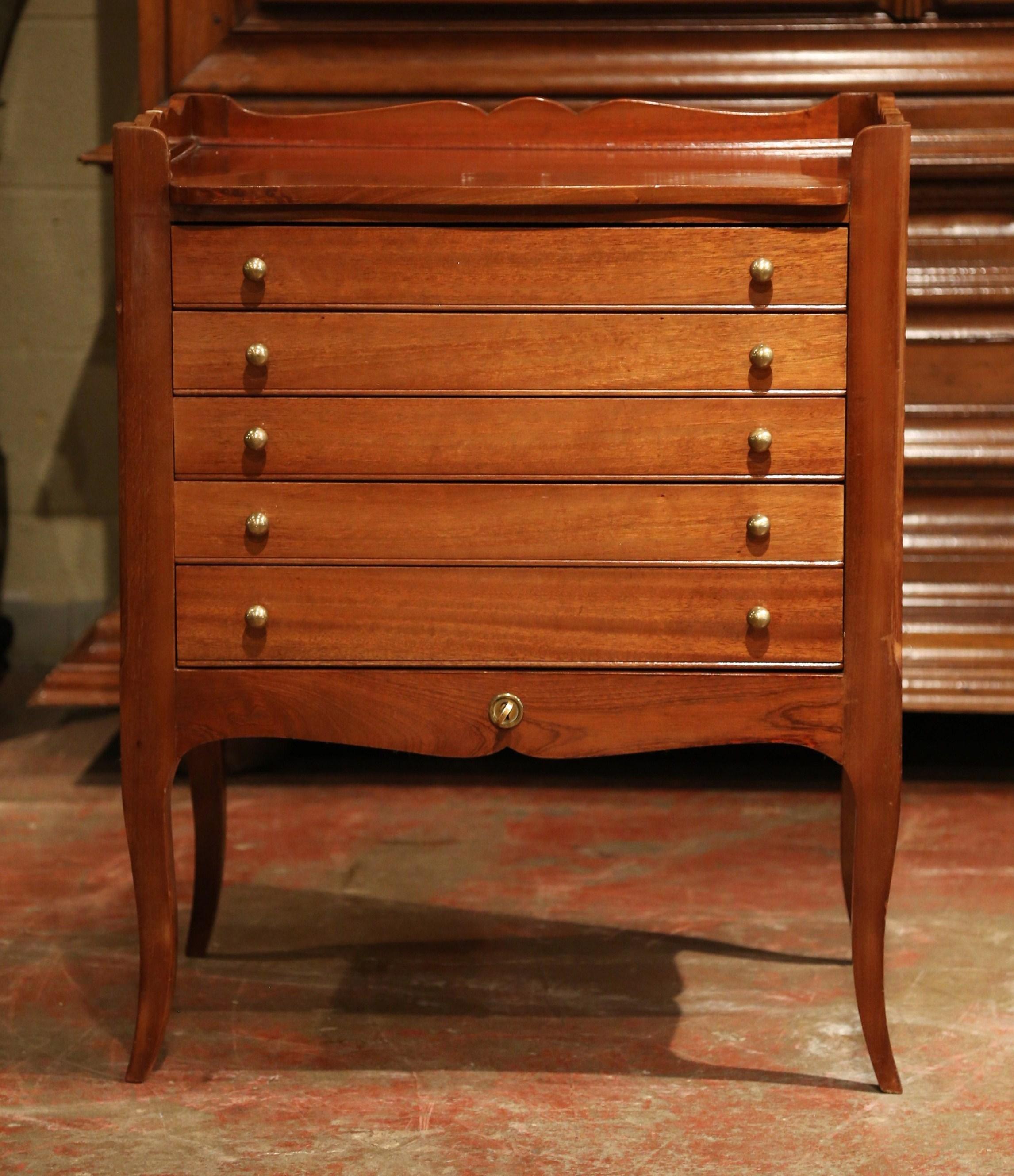 This commode with an included menagere flatware set was created in France, circa 1920. The traditional five drawer chest is an entertaining essential that keeps your flatware organized and well-preserved between uses; each drawer is upholstered with