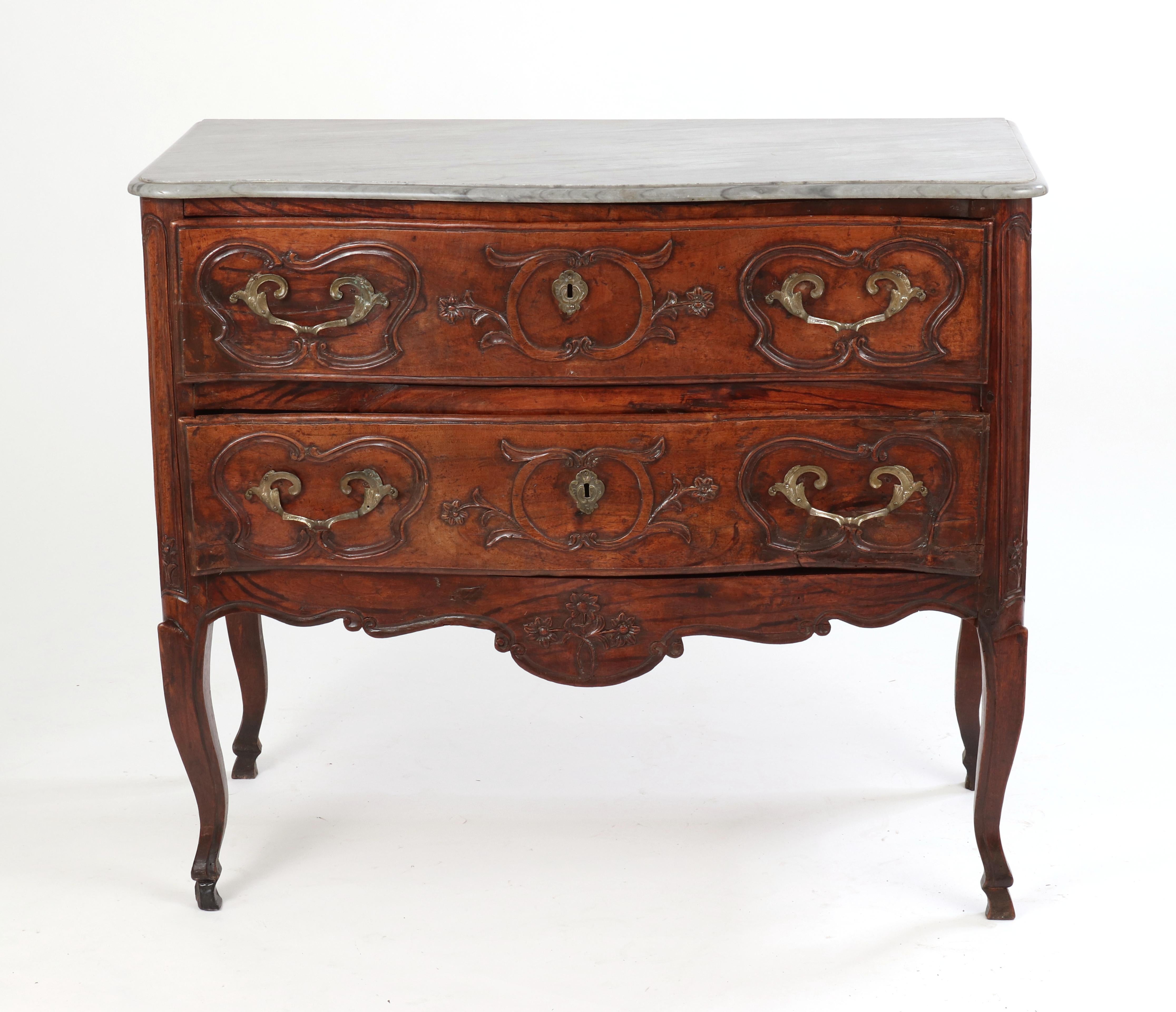Louis XV provincial walnut serpentine chest (commode sauteuse), the original marble top (blue turquin) over two 
drawers, each with replaced hardware set within carved cartouches; the cabriole legs ending in hoof feet joined by the floral carved