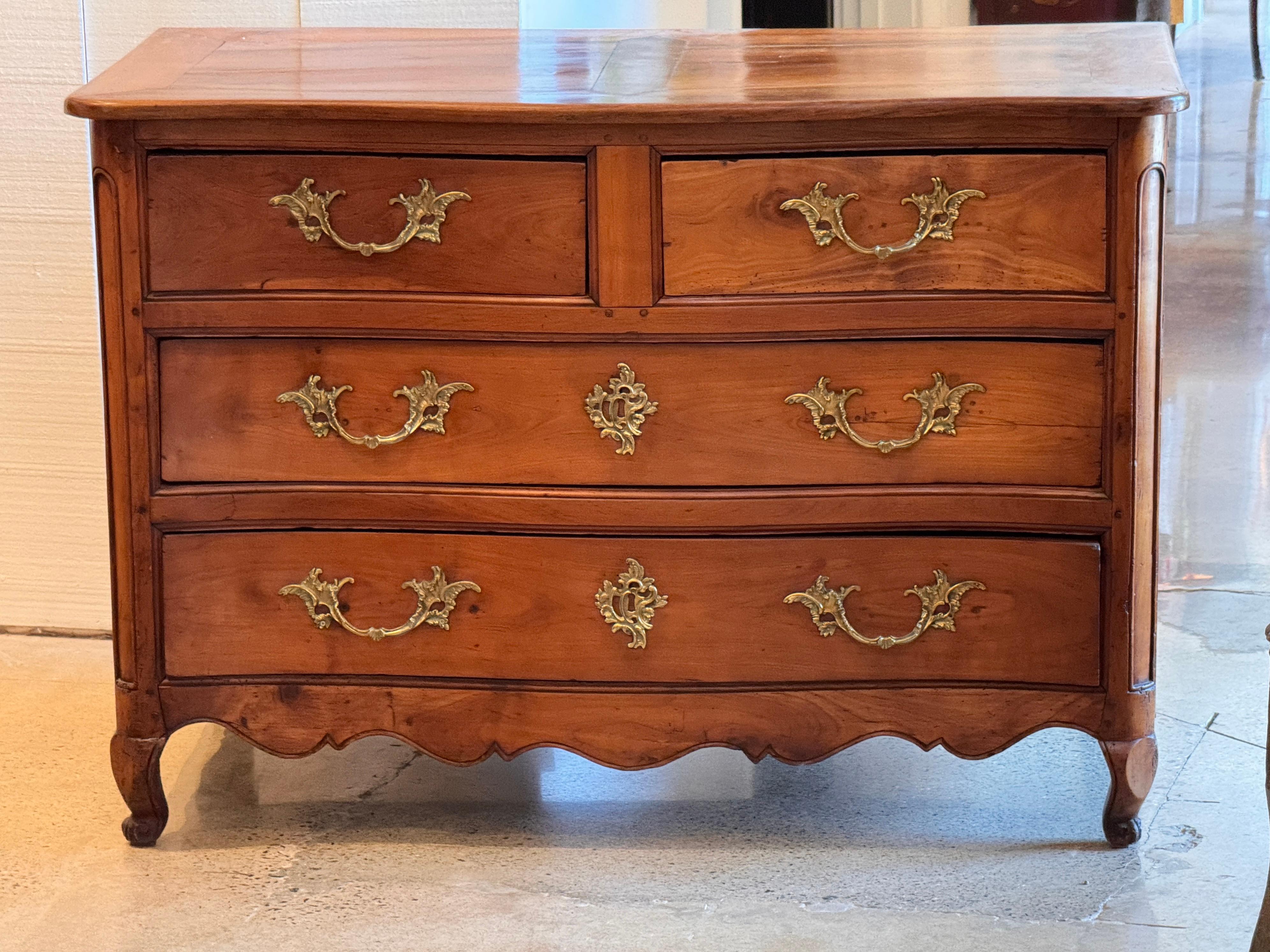 Commodo in noce di epoca Luigi XV, finemente lavorato, con fronte a serpentina e grembiule intagliato. Il pezzo presenta tre cassetti lunghi sotto due cassetti corti, tutti conservati con ferramenta originale in ottone in stile Rococò. Il piano