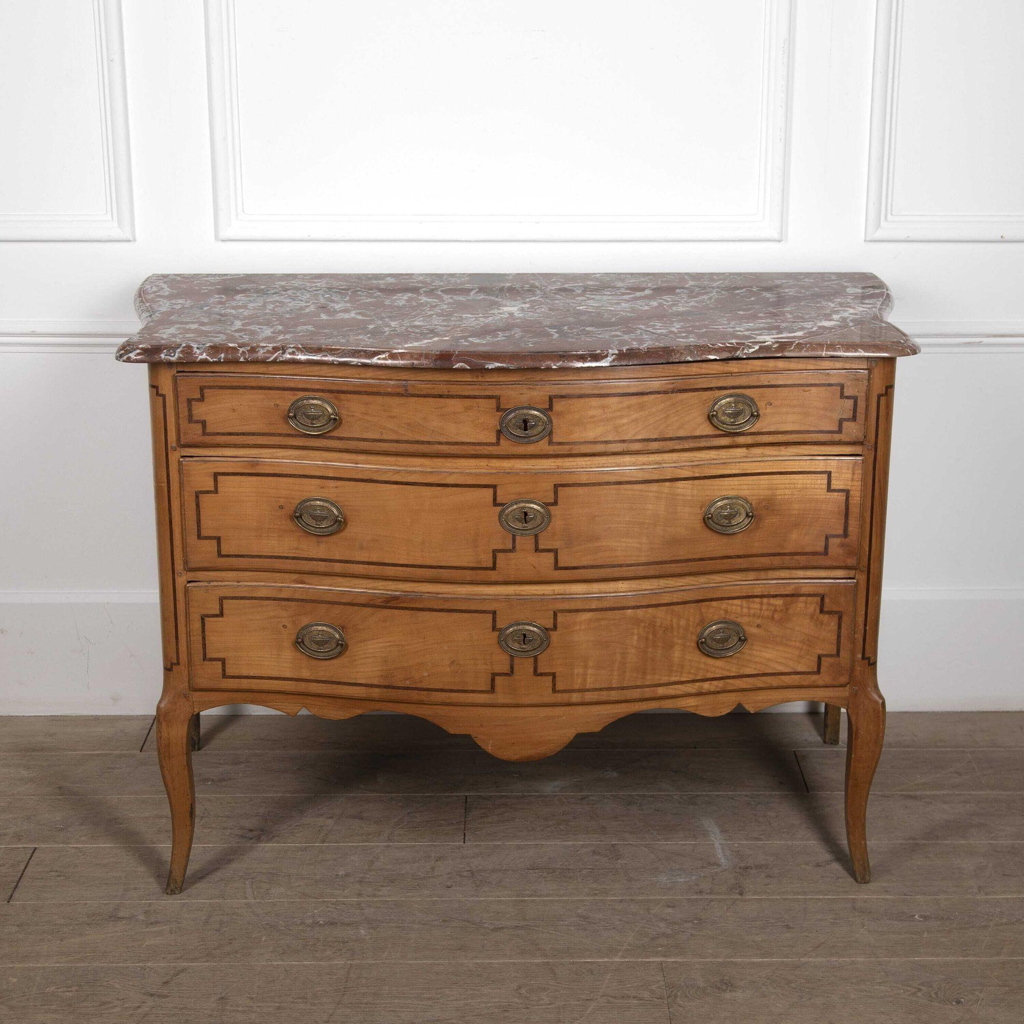 Louis XV/XVI transitional period commode is satinwood and serpentine in form standing on elegant cabriole legs.
The front and sides of the commode are inlaid with bold rosewood banding with re-entrant corners.
The later Sheriton style hardware is