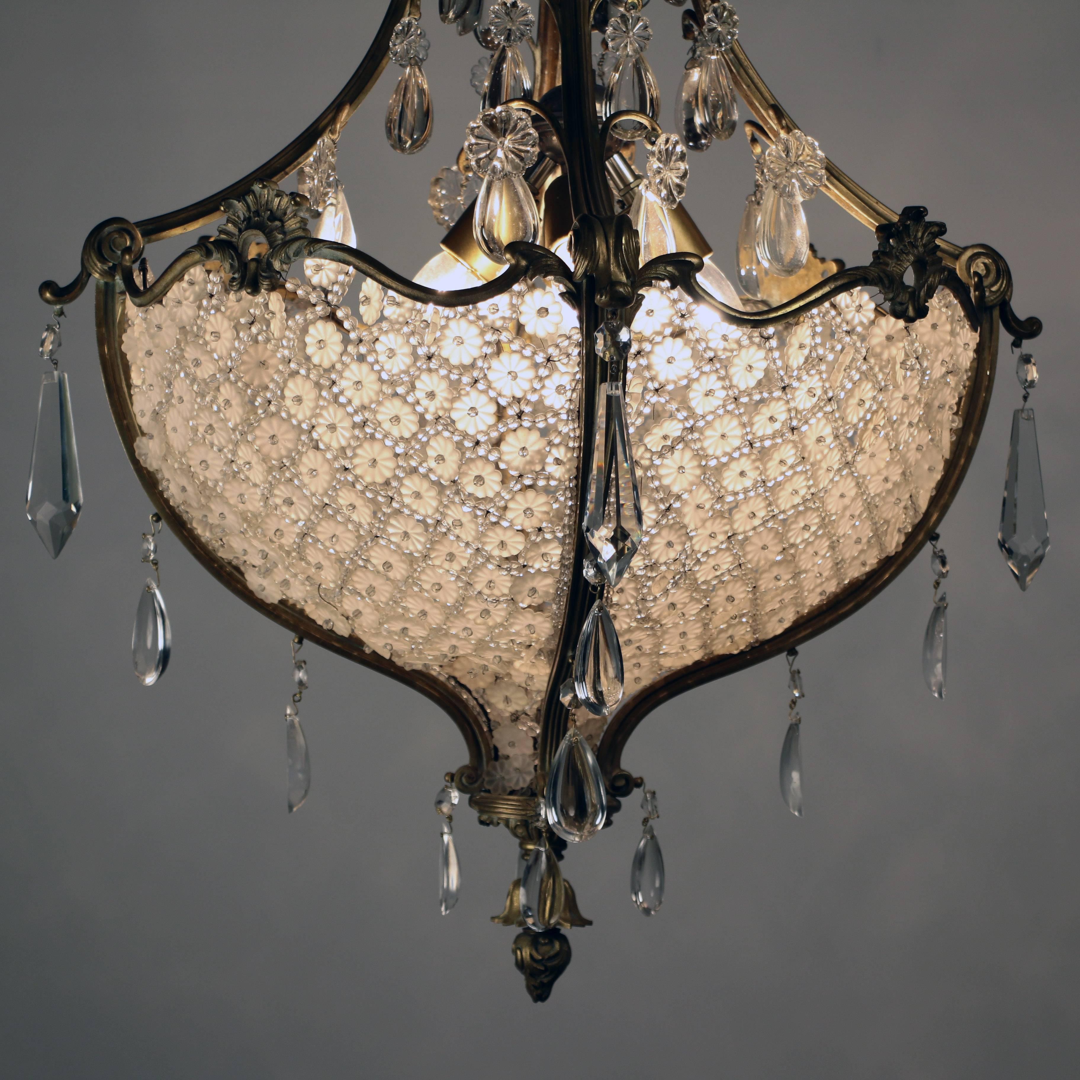 This sumptious chandelier from the Belle Epoque consists largely of a large hemispherical bag filled with basket weave crystals in a lattice of beads and flowerheads, the upper section complements and echos this arrangement.  The rim undulates which