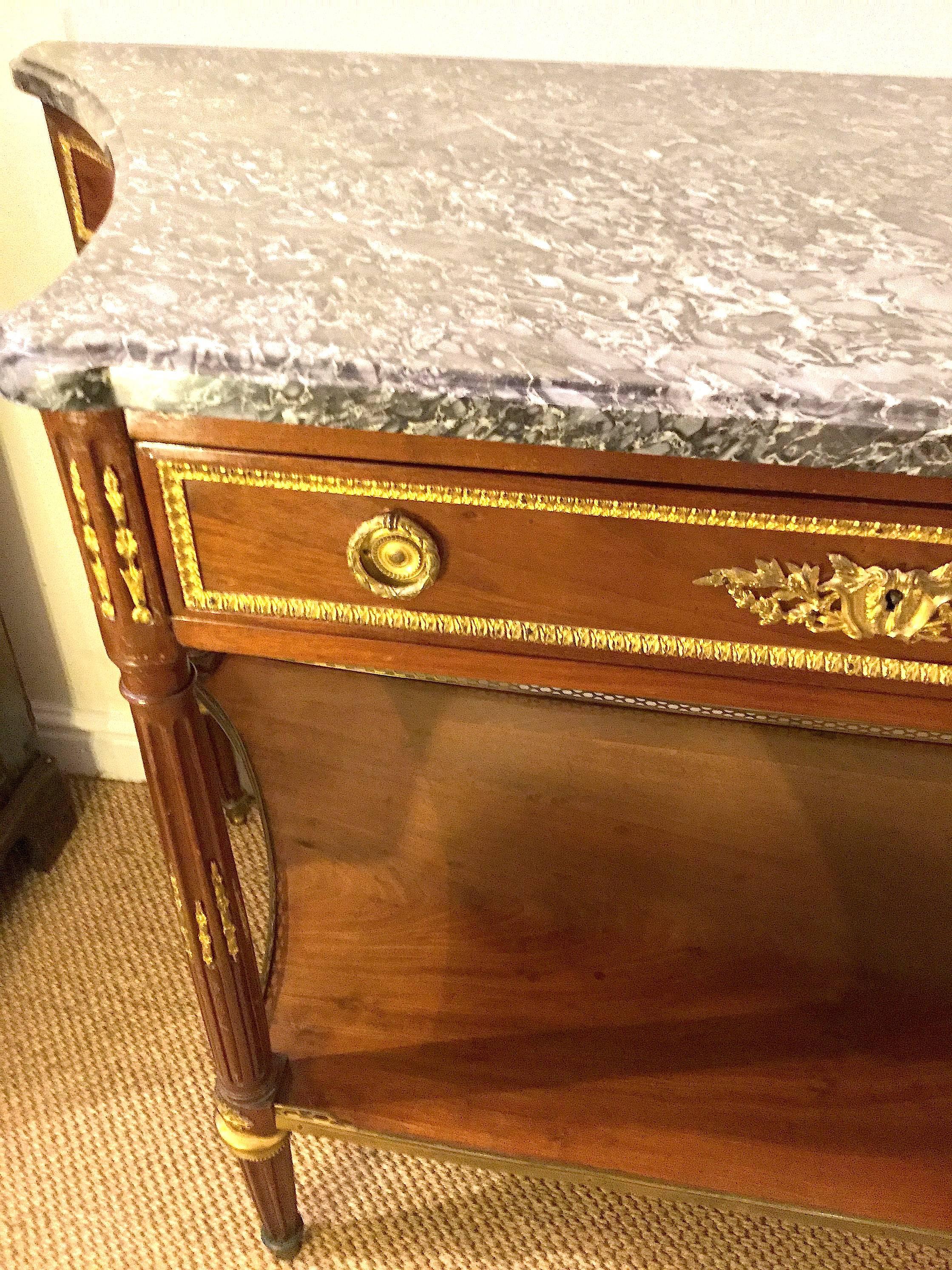 This Louis XVI ormolu-mounted 18th century console Desserte by Jean-Jacques Manser. dit. Mantzer with Saint-Anne des Pyrenees marble-top has a pierced brass galleried undertier. Beautifully decorated with gilt bronze trim to the legs and fluted