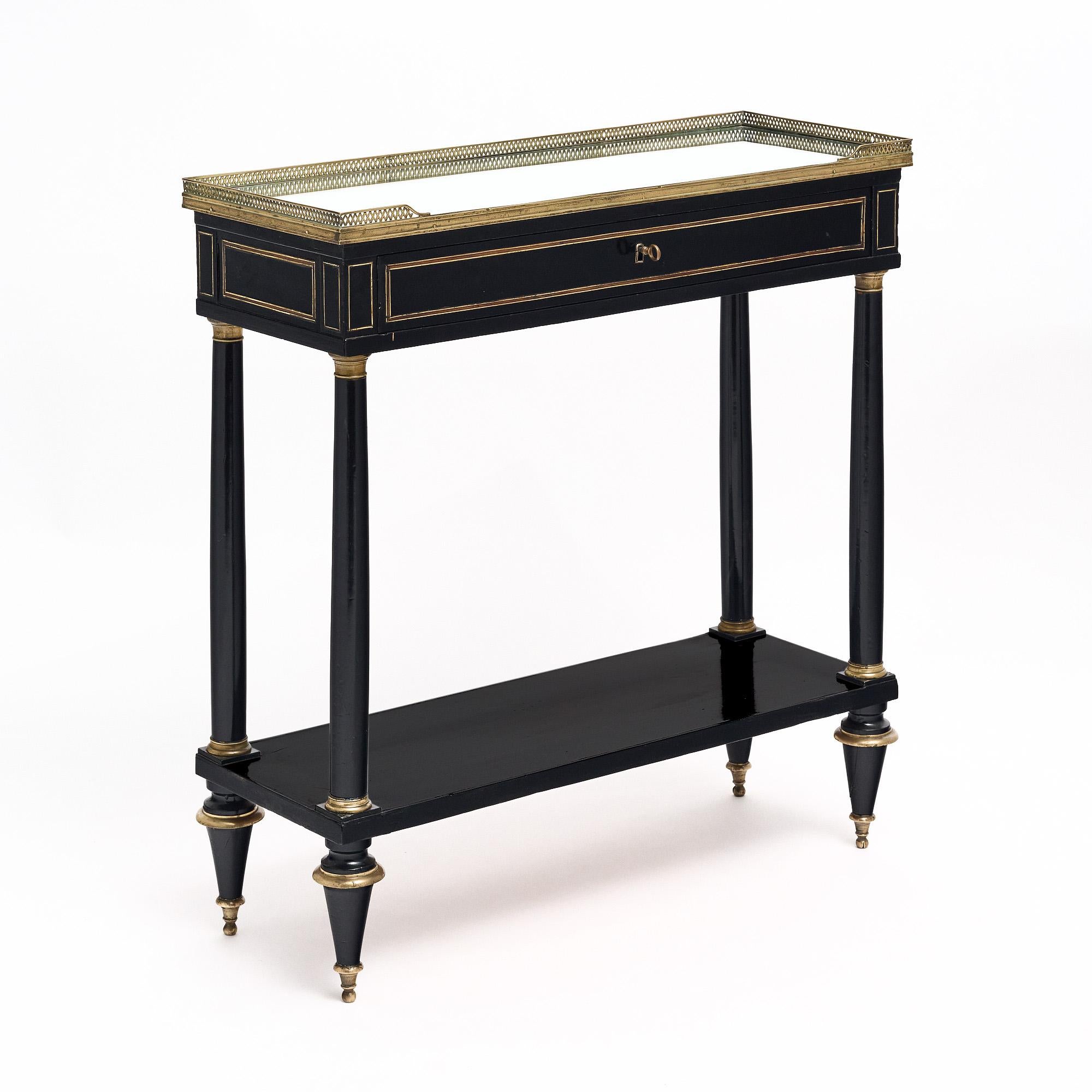 Console table from France in the Louis XVI style. This piece is finished with a lustrous museum quality French polish and is ebonized. There is a single dovetailed drawer with working lock and key. The four legs are tapered and support a lower shelf