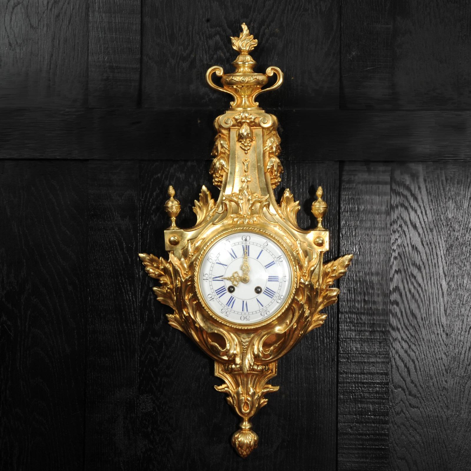 A large and impressive antique French cartel wall clock by A. D. Mougin. Beautifully modelled in the classical style of Louis XVI, in gilded bronze. Shield shaped with acanthus enveloping from the bottom, to the top a flaming urn.

The large dial is