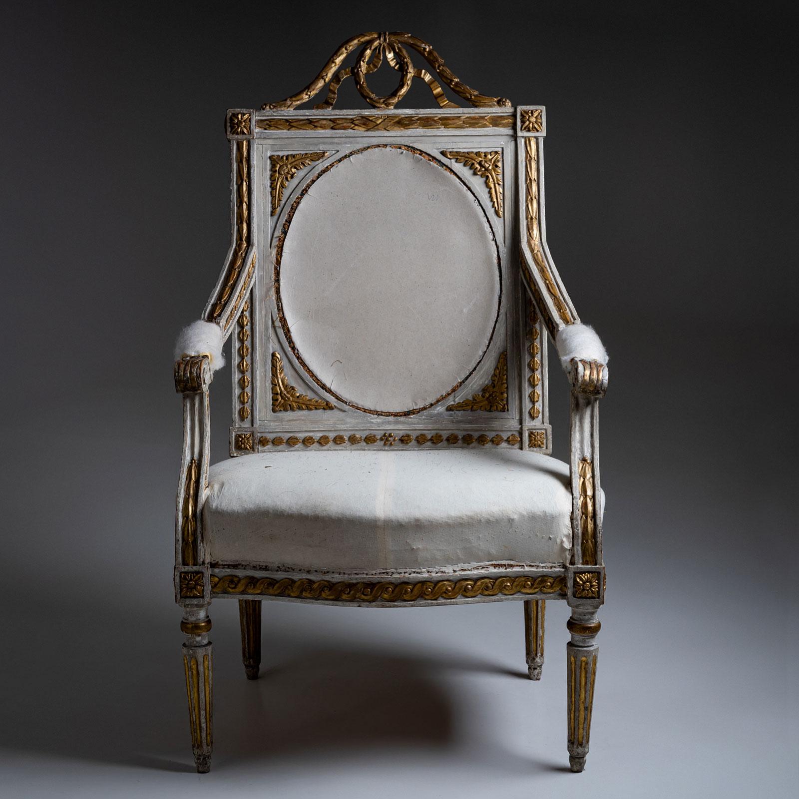 Elegant armchair from the Louis XVI period, featuring finely fluted legs and gently rising upholstered armrests. The rectangular backrest is richly adorned with a carved laurel wreath and festoons crowning its top. The intricately carved frieze