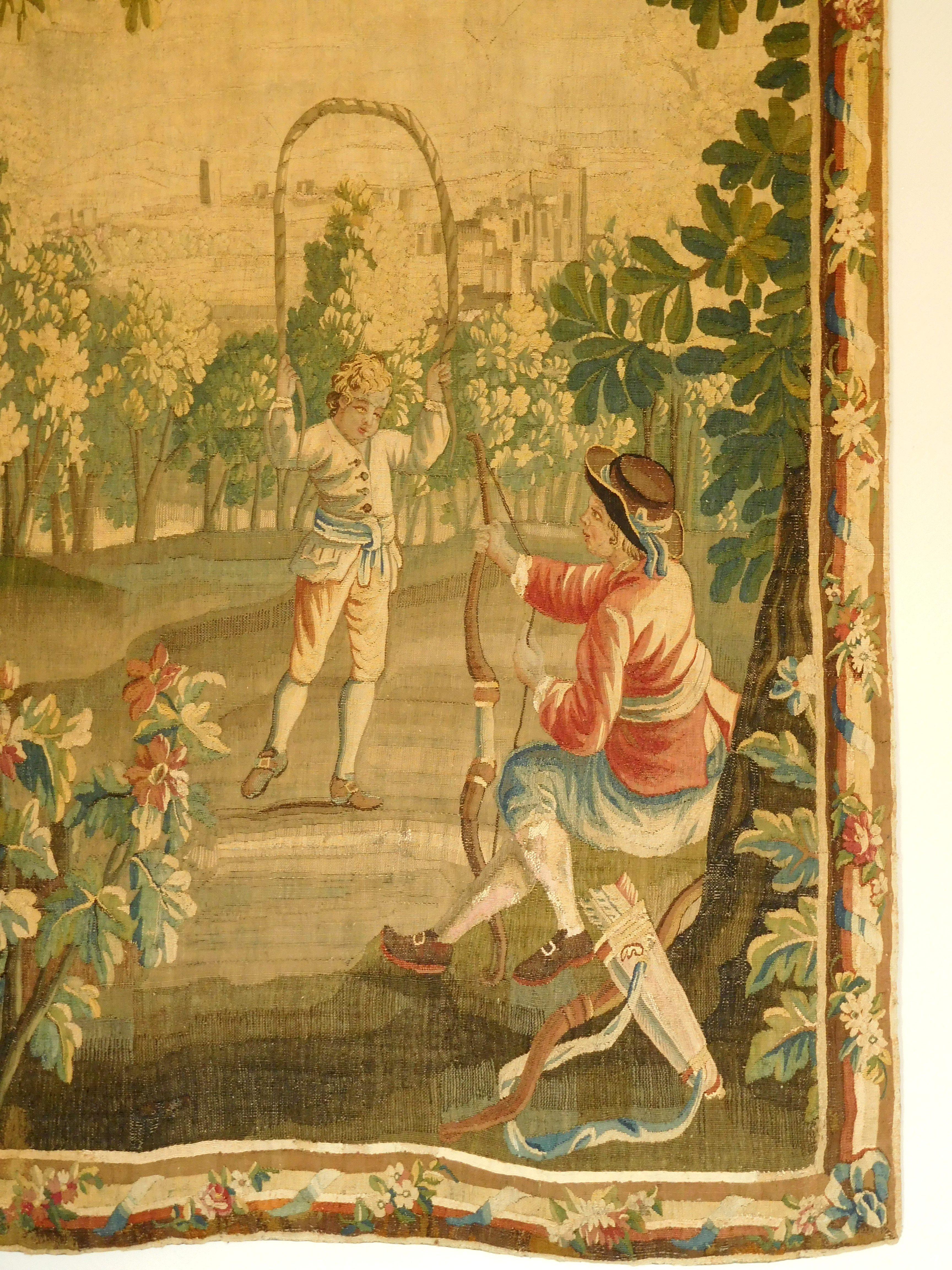 Charmante tapisserie en laine et soie - production du 18ème siècle (période Louis XVI vers 1780) attribuée à la Manufacture d'Aubusson.

Elle représente deux jeunes garçons jouant dans les jardins : l'un fait du tir à l'arc et l'autre joue à la