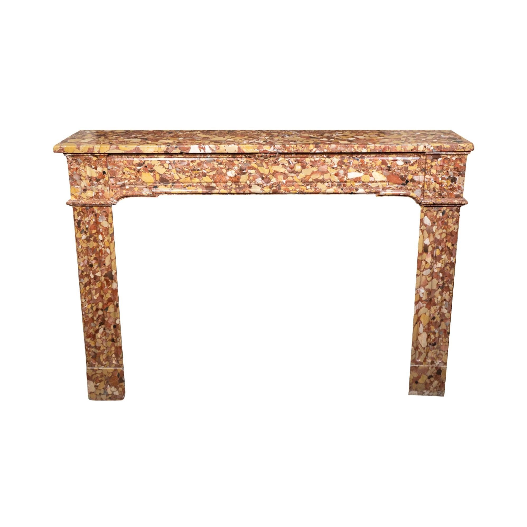 Cheminée de style Louis XVI en marbre Breccia d'Alep, originaire de France dans les années 1850. Cette pièce exquise présente un motif sculpté à la main ornant la clé de voûte, complété par des colonnes élégamment cannelées sur chaque pied,
