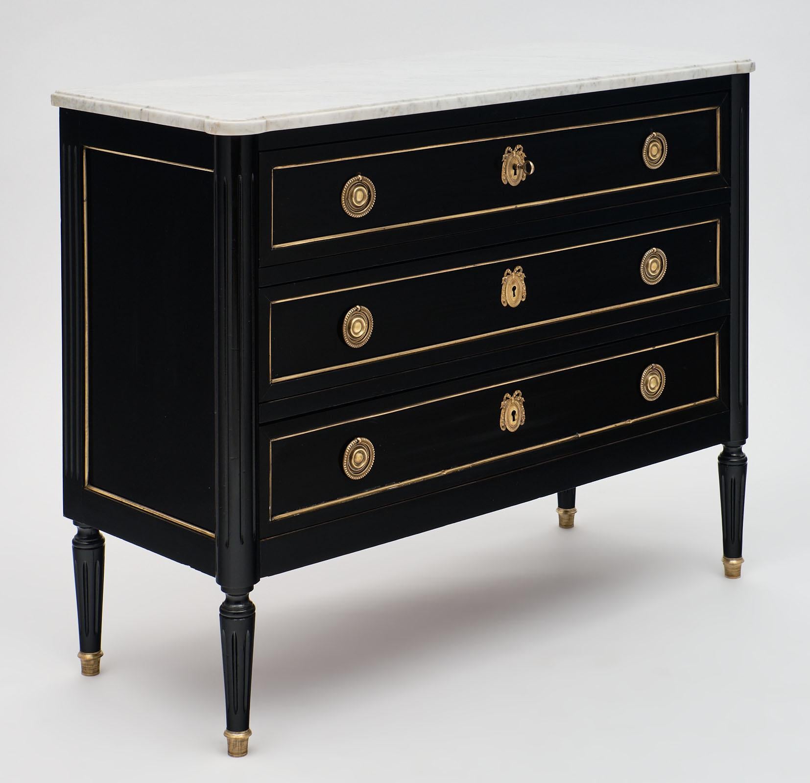 Carrara marble topped Louis XVI chest with a ebonized mahogany base and original brass trim and hardware throughout. The key and lock are in working order and add functionality to this classic case piece. It has been finished with a lustrous French