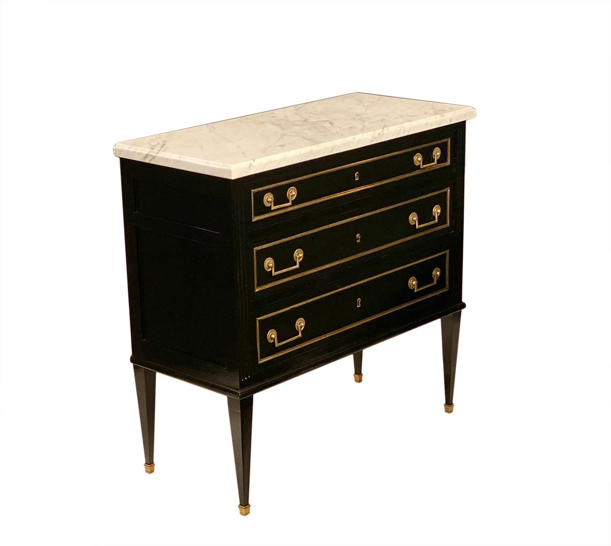 Louis XVI style Carrara topped chest. This lovely “commode sauteuse” from France is made of mahogany that has been ebonized and finished with a French polish. We love the gilt brass hardware and trim on all three dovetailed drawers. The long tapered