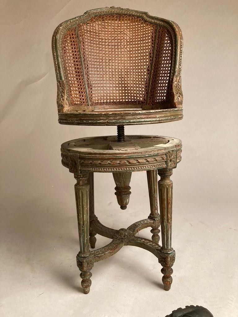 Charming 19th century French Louis XVI style carved and painted piano chair with caned seat and back. Lovely green painted finish, distressed with the patina of age. The four reeded lags are joined by an X-form stretcher, the seat turns to adjust