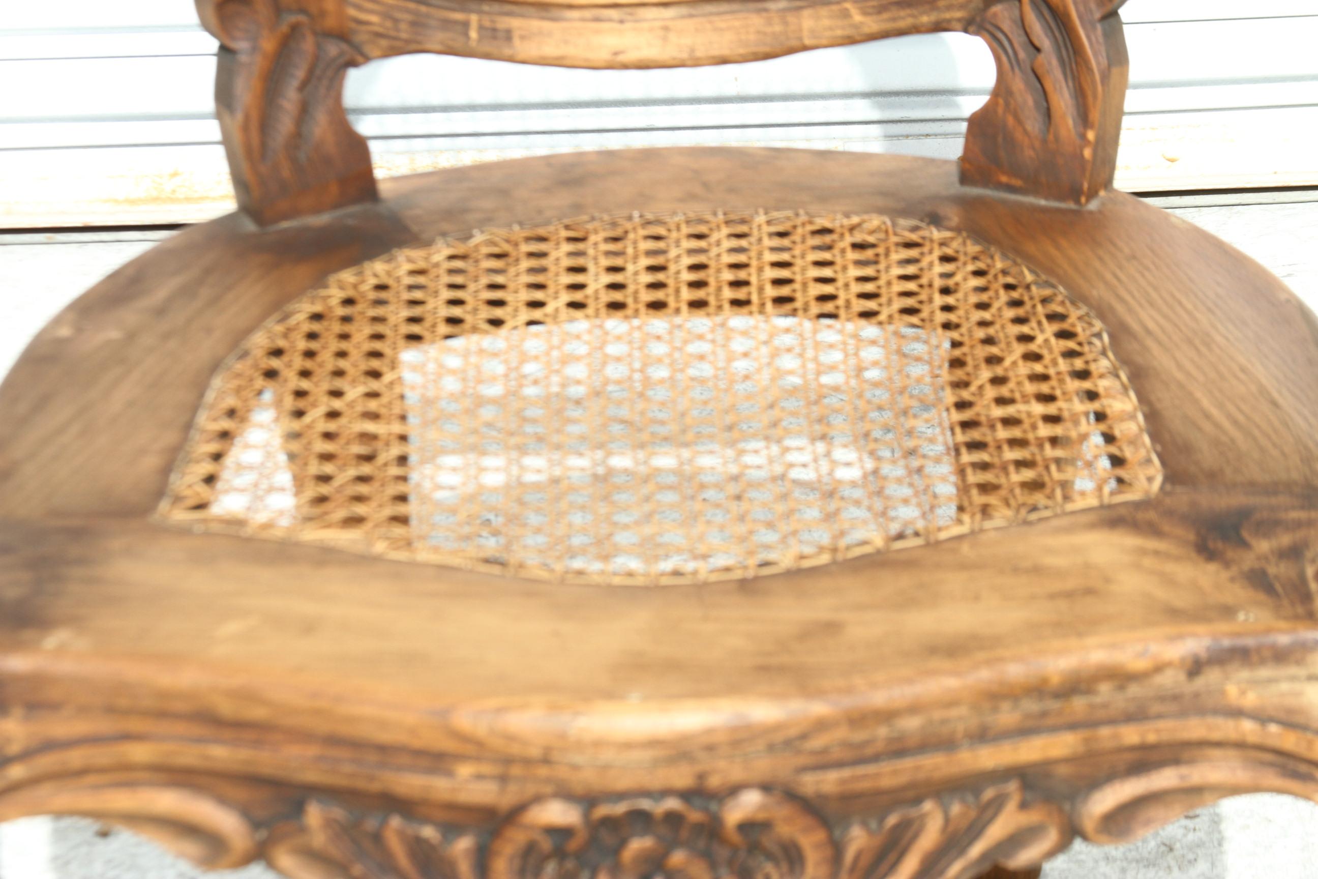Questo fauteuil è costruito in legno e canna. La seduta e lo schienale sono intrecciati in canna. Le braccia sono imbottite in tessuto. Lo stemma è intagliato. Anche la guida del sedile è ben intagliata. Le gambe sono realizzate in stile provinciale
