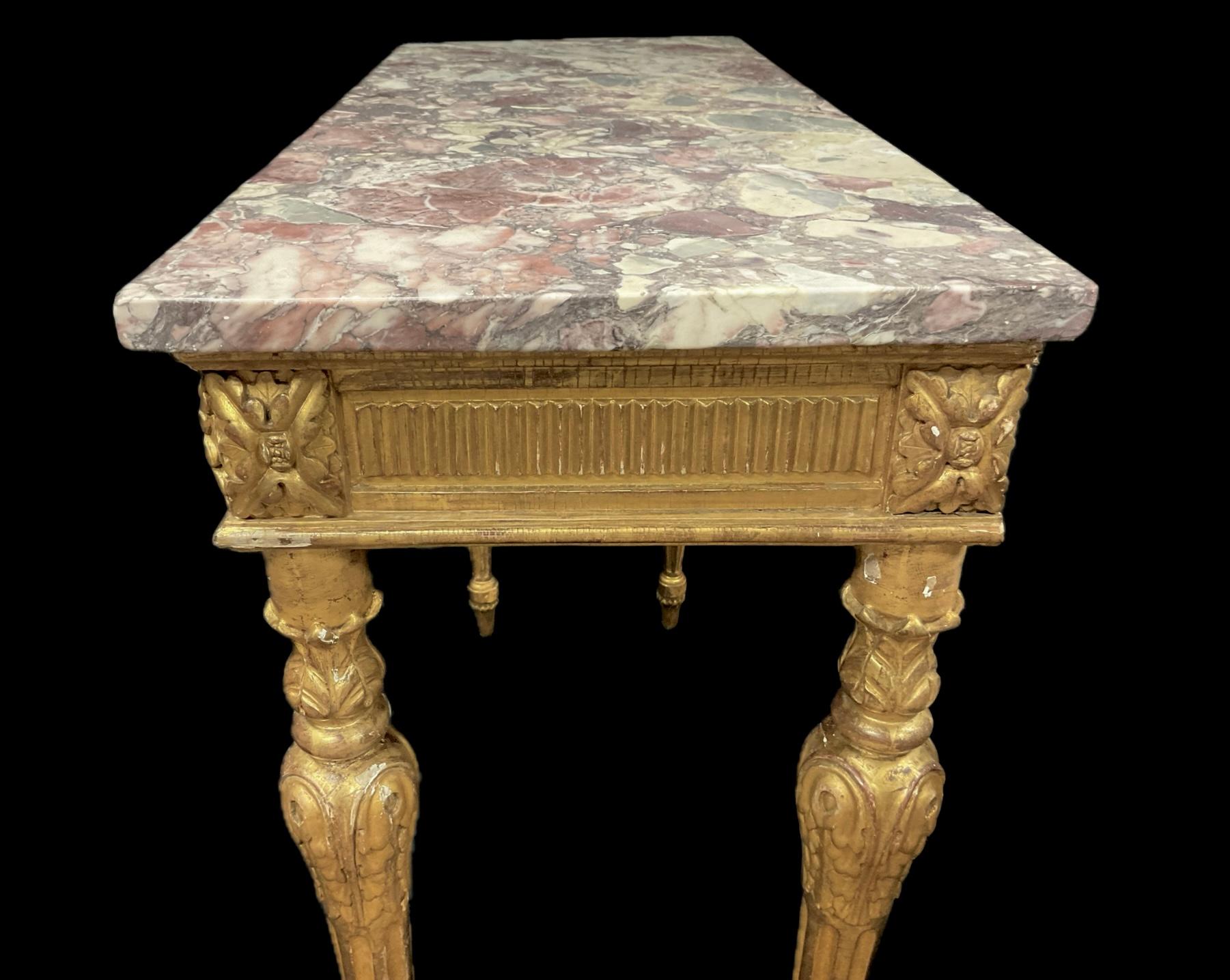 Tavolo consolle in legno dorato Luigi XVI del XVIII secolo con piano in marmo. Il tavolo presenta un piano in marmo Rouge cesellato a mano su un grembiule e una base in legno dorato intagliato.  Il piano in marmo poggia su un fregio scanalato