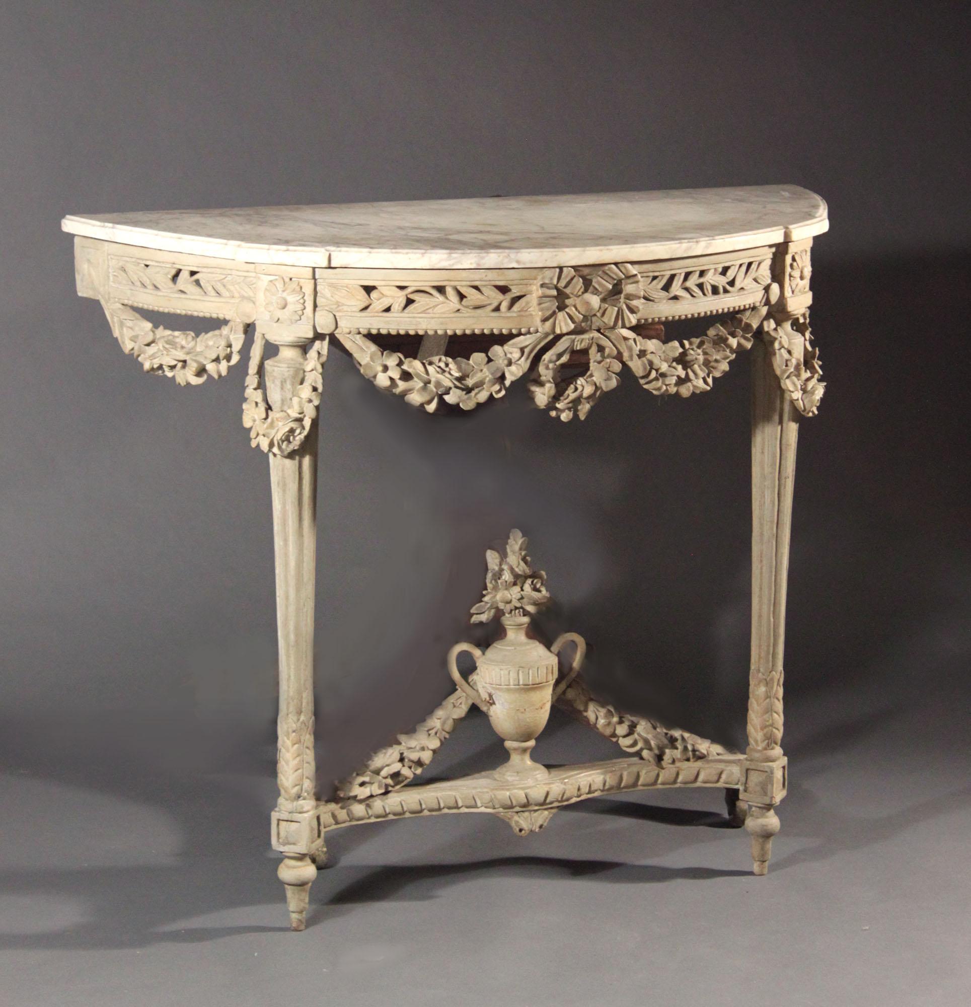 A Louis XVI period console table with its original Carrara marble-top; old grey paint with signs of the original gilding underneath. Superb carving: the pierced frieze with leaves and garlands of flowers, turned and fluted legs, twin handled vase