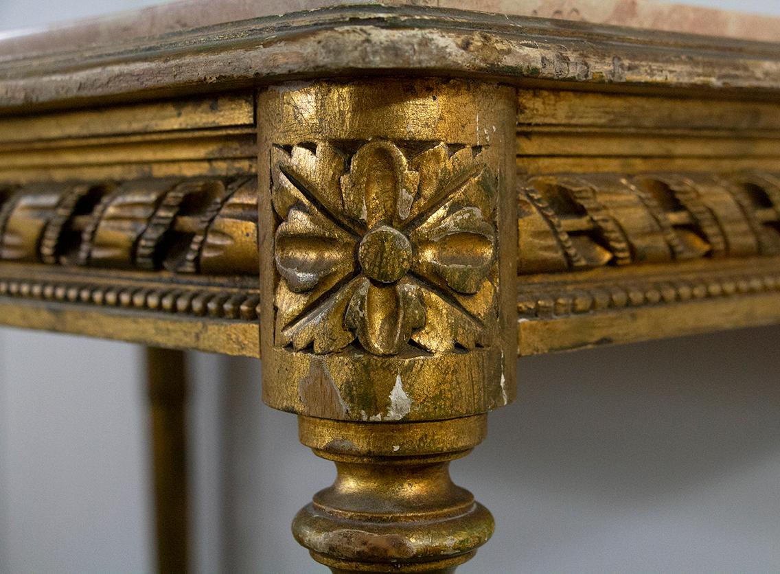 Schöner Mitteltisch oder Konsole im Louis XVI-Stil aus vergoldetem Holz mit Marmorplatte. Er ist als Gürtel mit einem Bandfries gestaltet und ruht auf vier kannelierten Füßen, die mit Palmen gekrönt sind, die durch eine Klammer verbunden