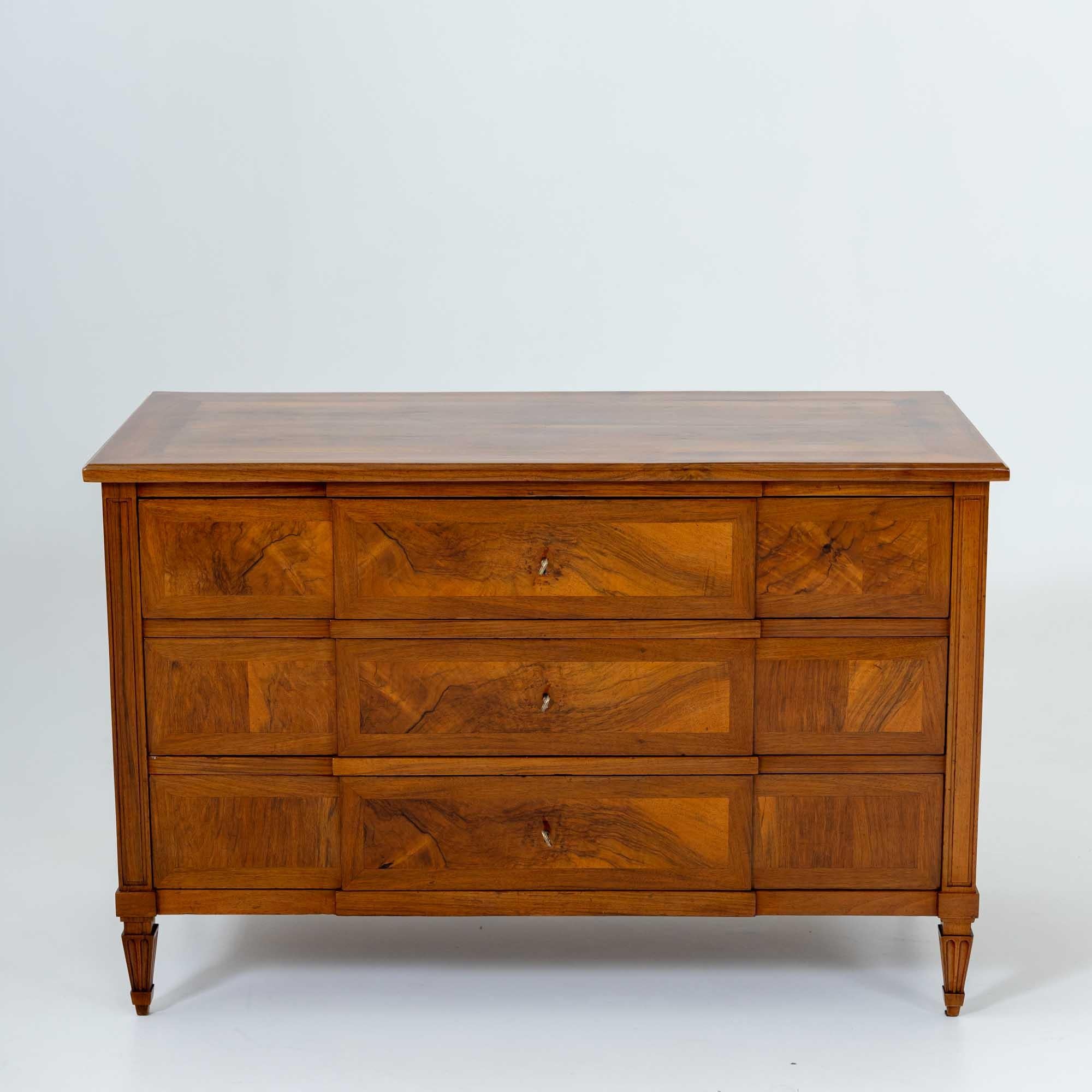 Large Louis XVI chest of drawers with three drawers standing on square tapered feet. The pilaster strips and legs of the chest of drawers feature carved frame decoration and fluting. The drawer fronts are accentuated by a slightly protruding central
