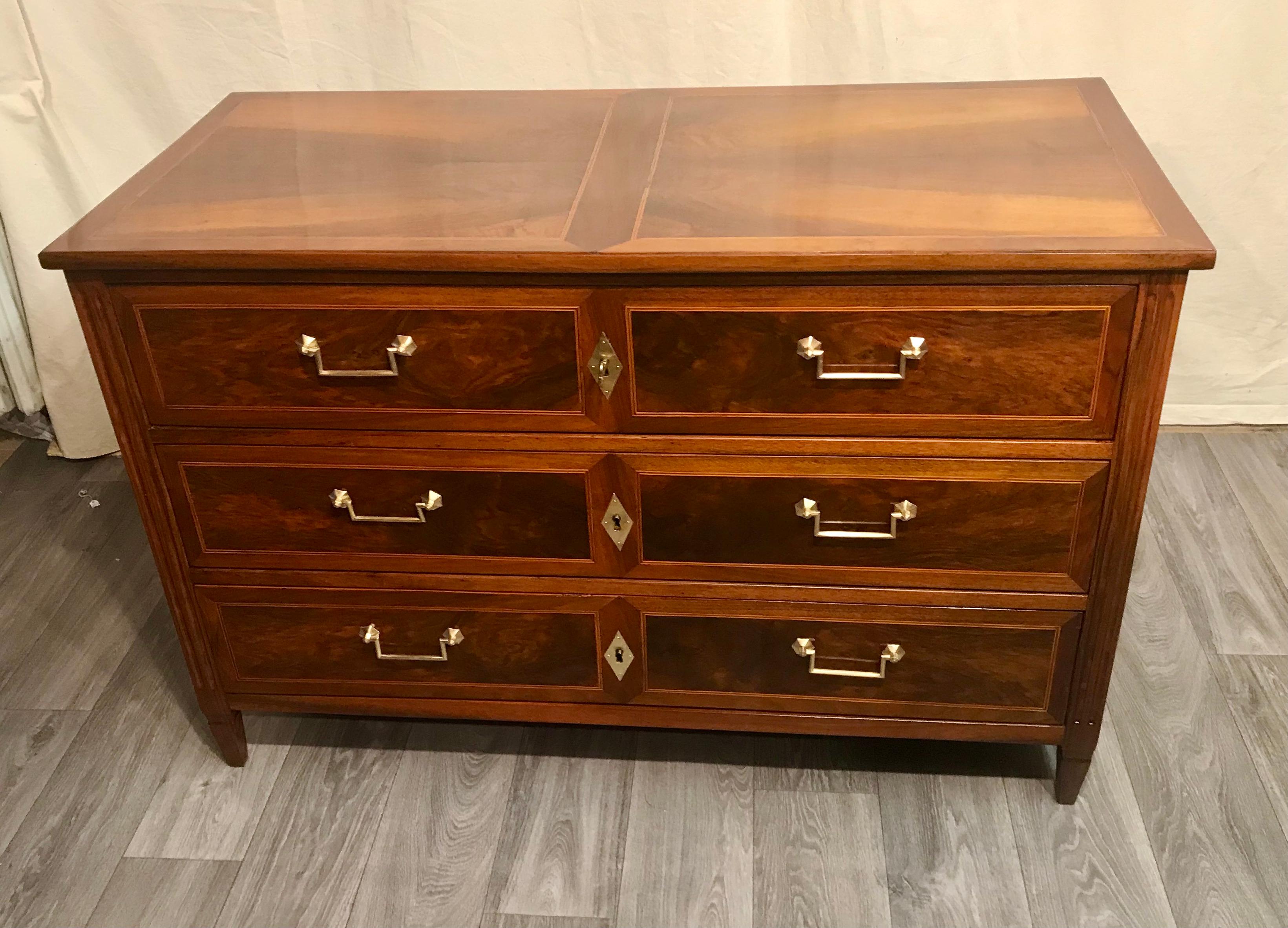 This original Louis XVI chest of drawers dates back to 1780 and comes from the southern part of Germany. 
The three drawer commode has a sleek design and stands on four pointed feet. It has a very pretty walnut veneer which is embellished with