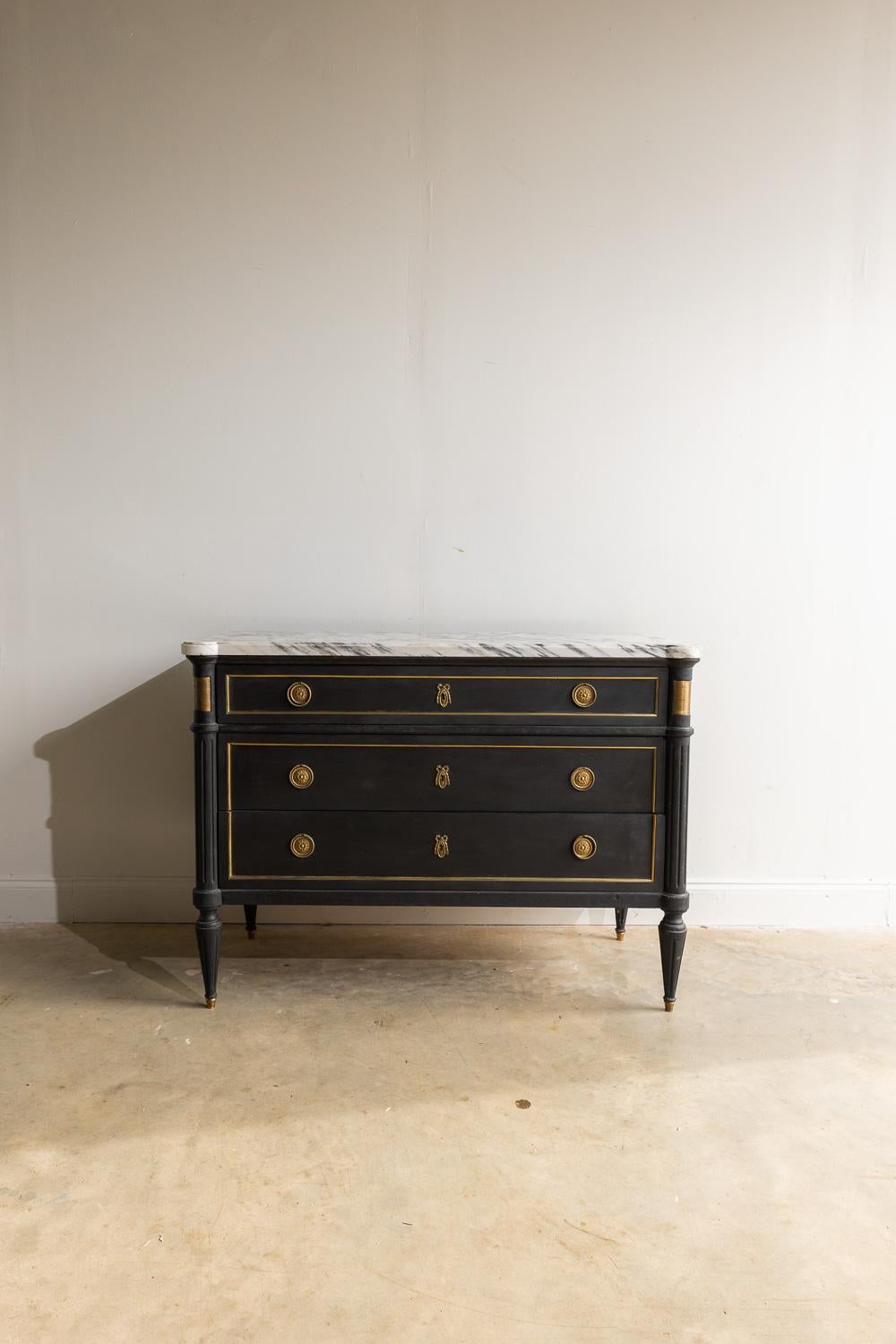 This piece is truly a sight to behold! The moody marble top, black paint, and gold accents give this piece such a unique feel. All of the original hardware is a beautiful worn gold color. There are 3 large working drawers. The top drawer has a