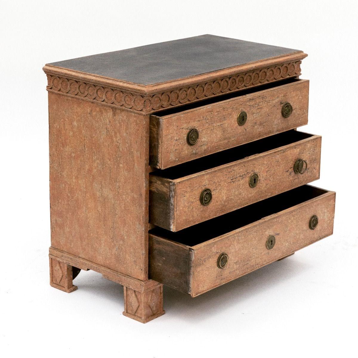 Cassettiera Luigi XVI con colore dipinto a rosa sul corpo.
Piastra superiore verniciata di nero.
Sotto il piano superiore, anelli rotondi intagliati in legno. 3 cassetti con finiture in ottone, gambe con riempimenti a rombo, serrature