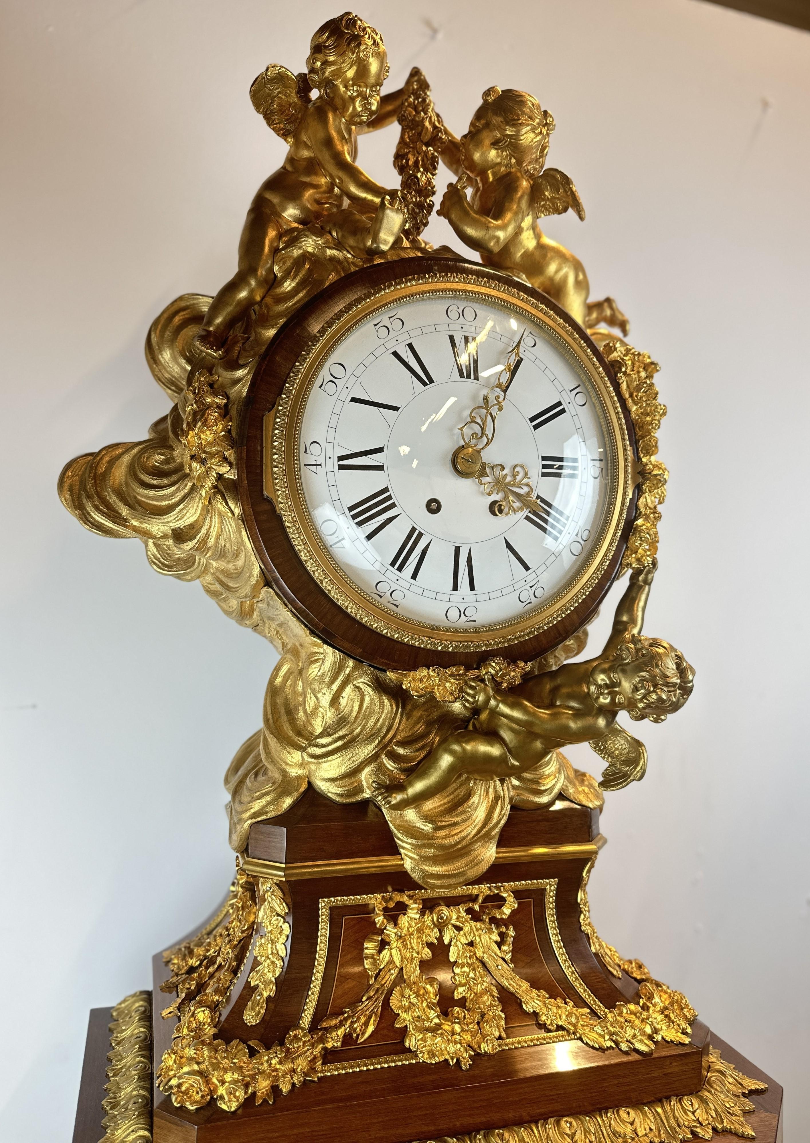 Spectacular mahogany grandfather clock, decorated with numerous high quality gilded bronze fittings. The dial is surrounded by superb gilded bronze frames representing three cherubs in the middle of the clouds. The pedestal case below the clock face