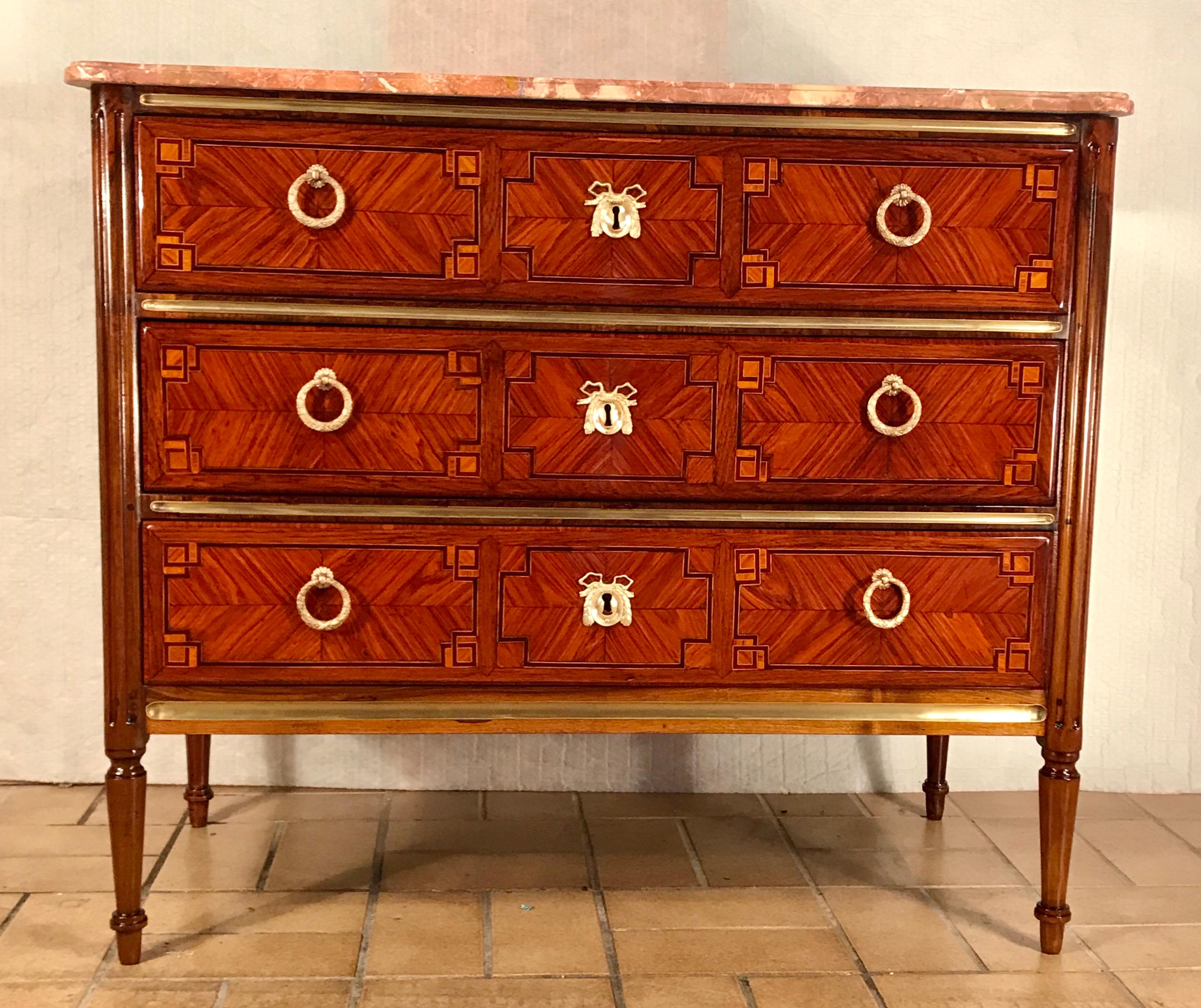 Louis XVI Commode, France, 1780.
This exquisite three drawer original Louis XVI commode is standing out for its beautiful geometric kingwood marquetry on front and sides.
The fluted legs are made of walnut. The brass fittings as well as the marble