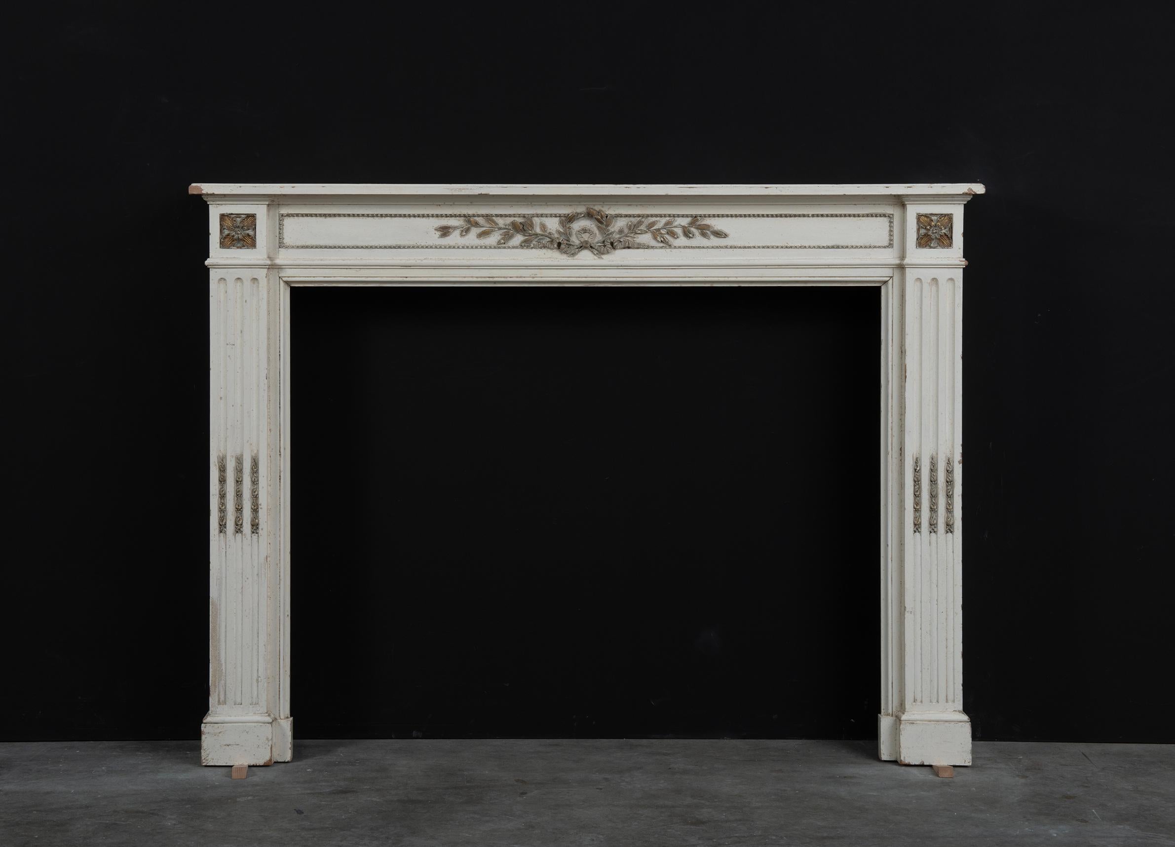 Very nice and pleasant wooden Louis XVI fireplace.

This fireplace comes with loads of patina and beautifully well aged gilded details.
The nice straight profiled topshelf rest on a super decorative frieze with elaborate gilded foliage in the center
