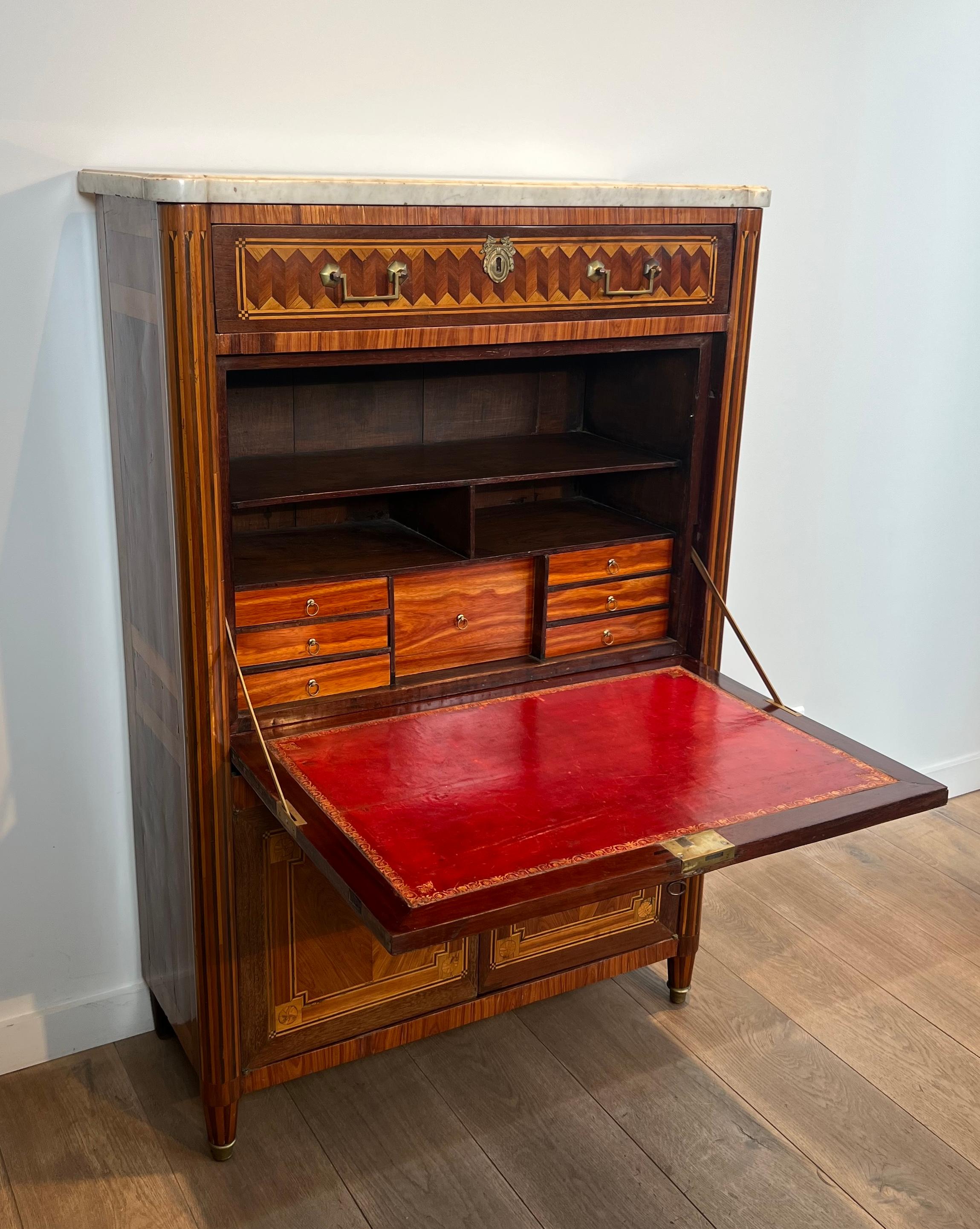 Questa bellissima segretaria a ribalta intarsiata è composta da una struttura in Oak, che si apre con un cassetto, un'anta a ribalta e due ante inferiori.  con una lastra di marmo di Carrara in cima. 
Questa è un'opera francese. Periodo Luigi XVI,