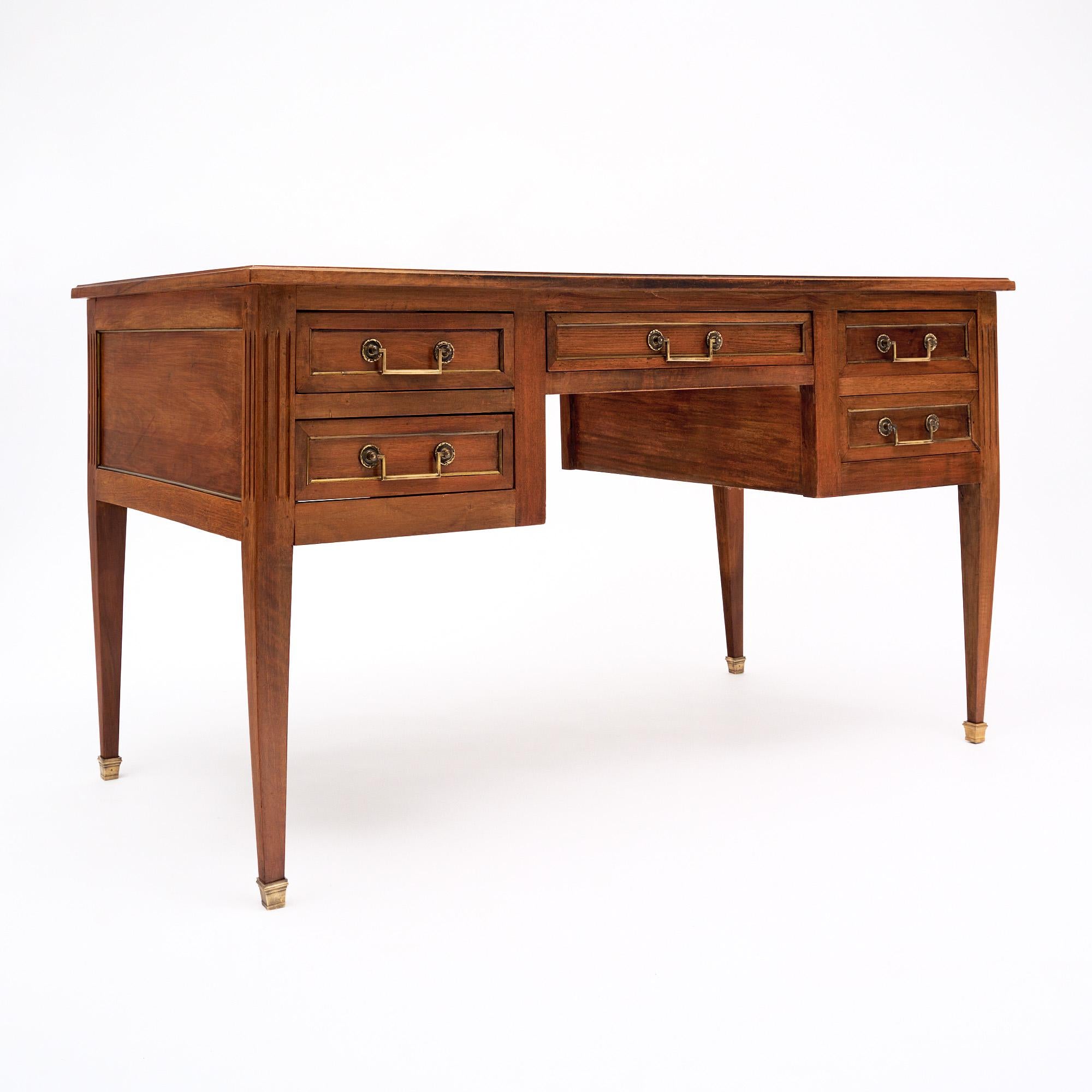 French Louis XVI style writing desk made of solid wood construction; primarily cherry wood. It has been finished with a lustrous French polish of museum quality. The top features a green leather writing surface original to the piece. There are four