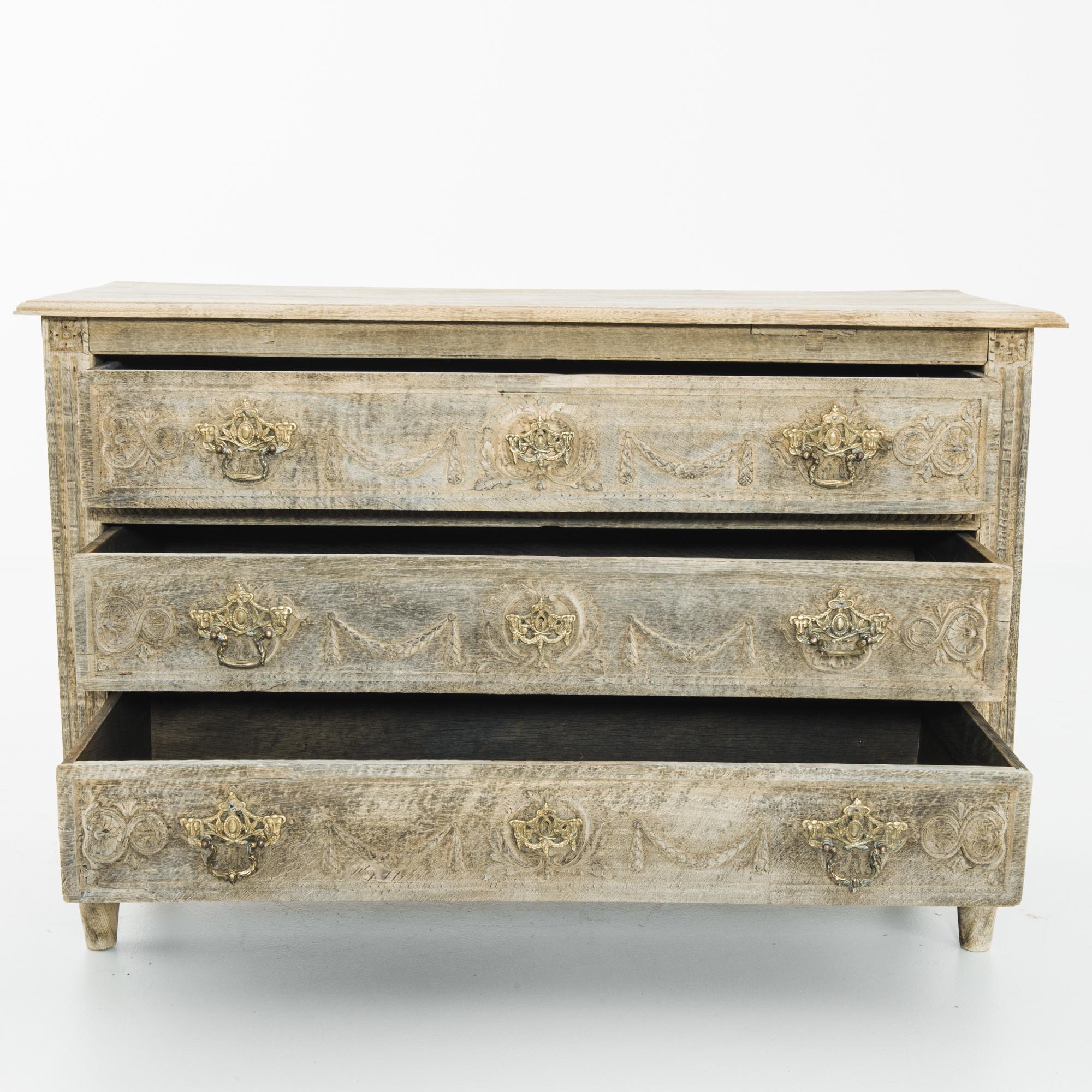 A three drawer oak chest from France, circa 1820 in the Louis XVI style. Distinctive period design is highlighted by the unique finish, the wood has been restored in our workshops to a natural color, retaining its timeworn patina and complimenting