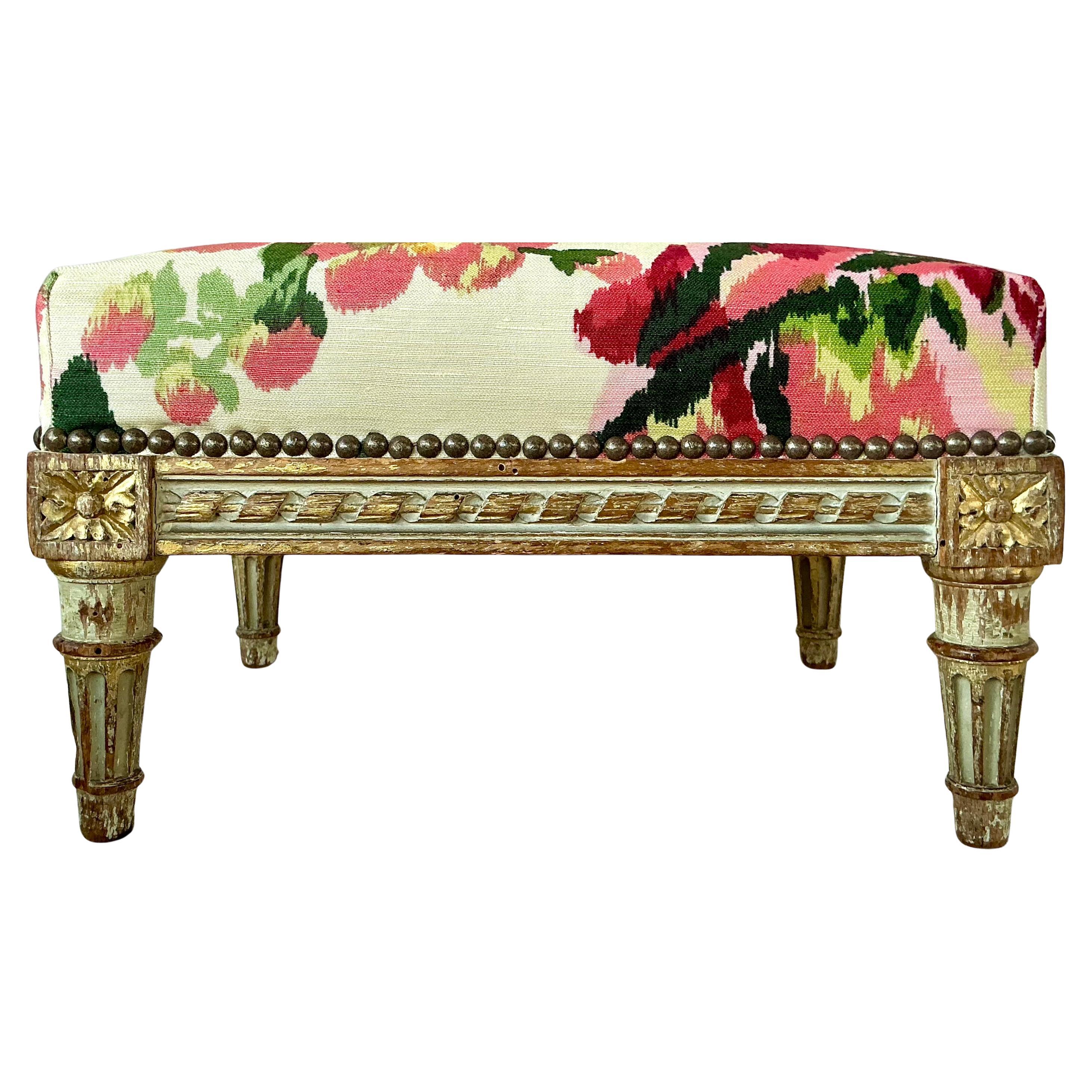 Pareja de Reposapiés Franceses Esculpidos Estilo Luis XVI. Los reposapiés presentan marcos pintados y dorados maravillosamente envejecidos. Cada taburete presenta detalles clásicos de Luis XVI, como patas cónicas estriadas, rosetones tallados en las